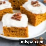 A slice of gluten-free dairy-free pumpkin cake with frosting and a bite taken out.