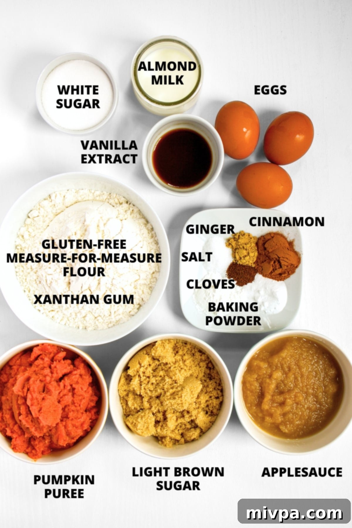 All the dry and wet ingredients for the gluten-free pumpkin cake recipe laid out on a white board.
