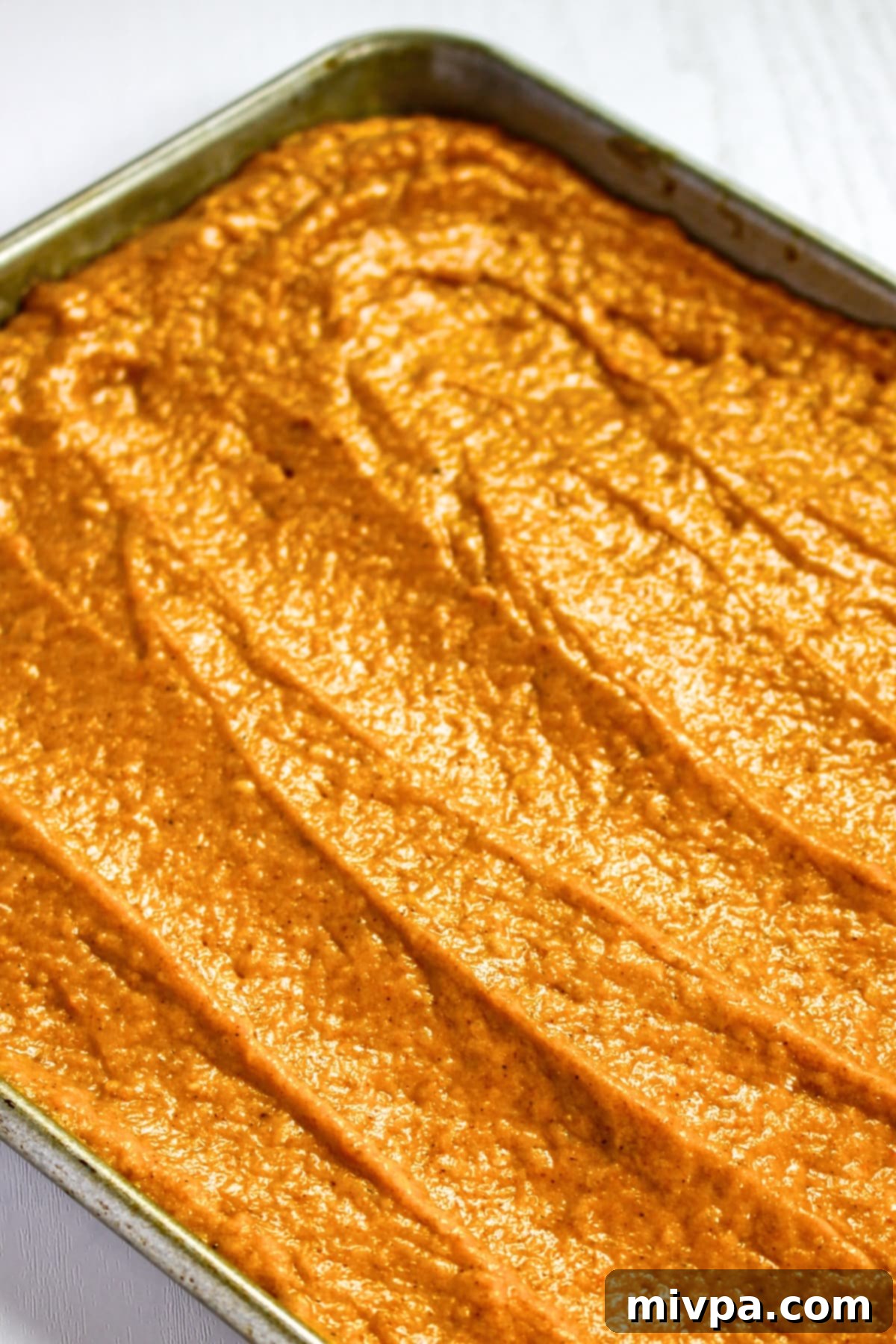 Smooth gluten-free pumpkin cake batter spread evenly in a baking pan.