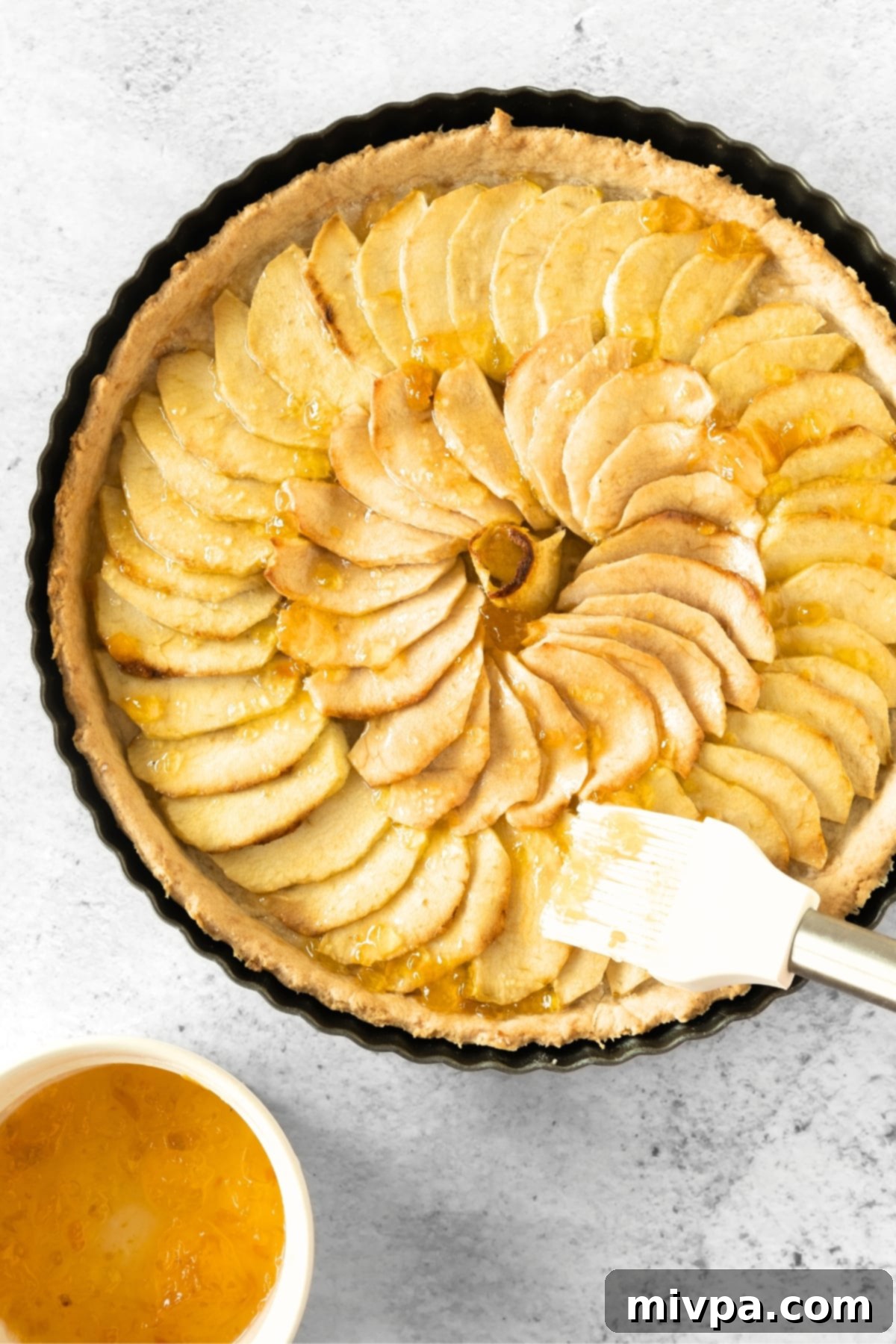 Gluten-Free Apple Tart (Dairy-Free) Brushing baked apple tart with apricot preserves for a glossy finish.