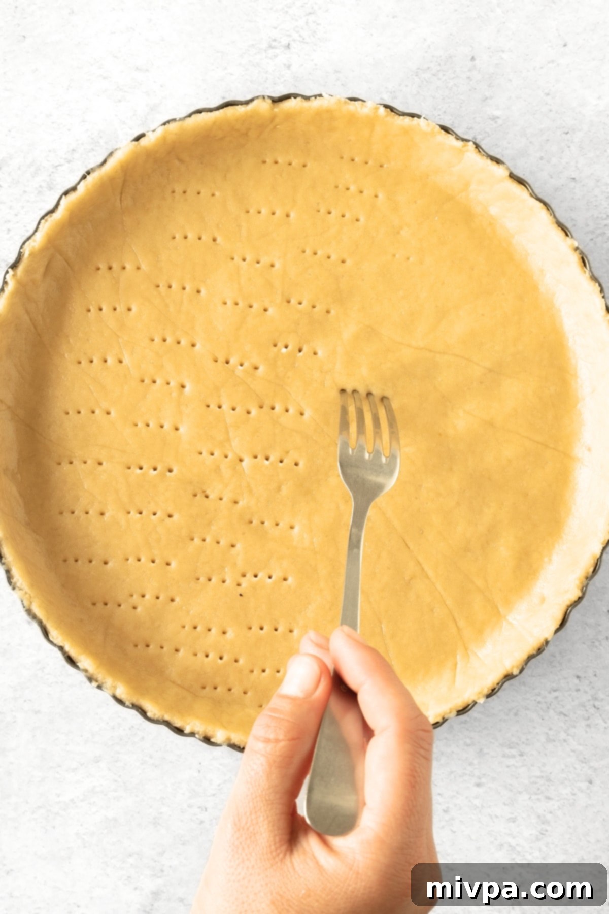 Gluten-Free Apple Tart Recipe (Dairy-Free) Poking holes in tart crust dough with a fork.