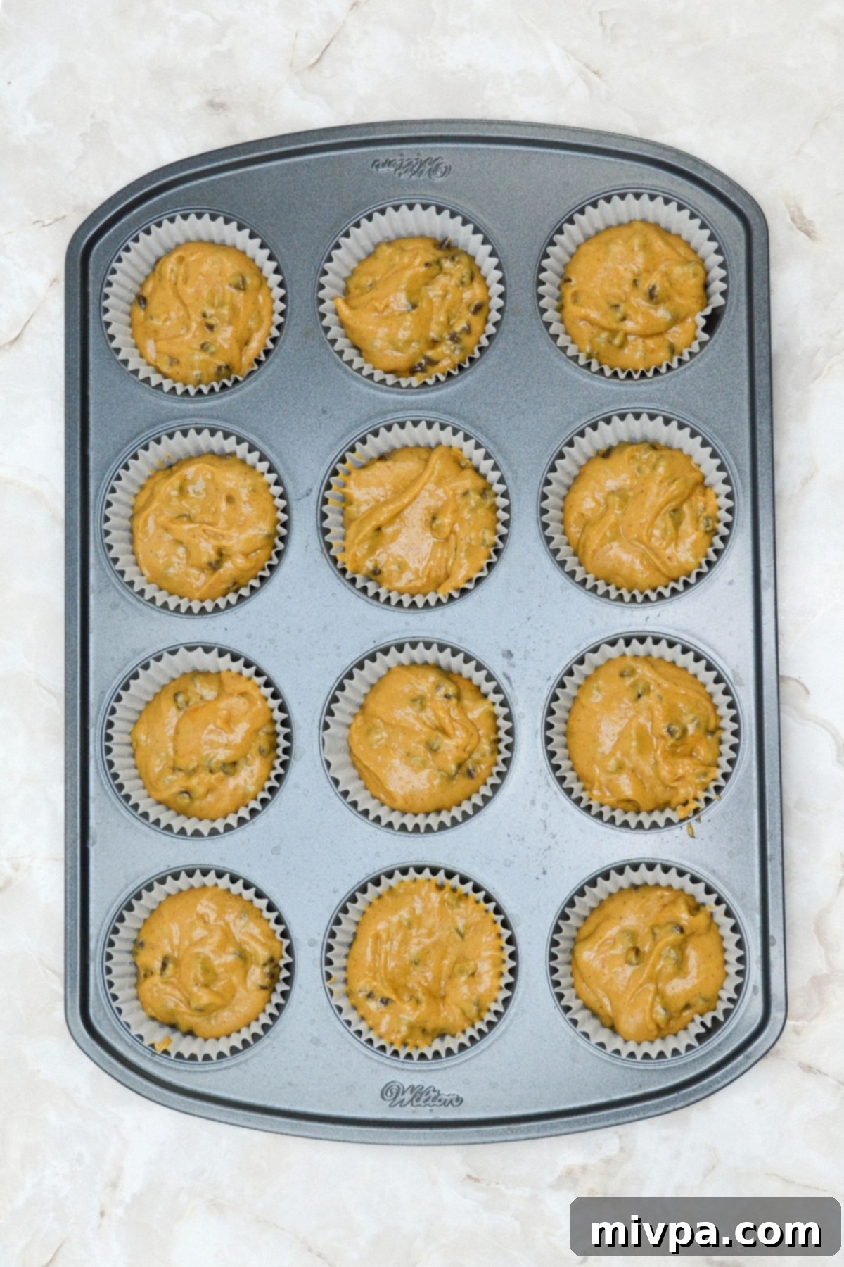 Gluten-Free Pumpkin Cupcake Recipe (Dairy-Free) Pumpkin cupcake batter with chocolate chips scooped into cupcake liners in a baking pan, ready for the oven.
