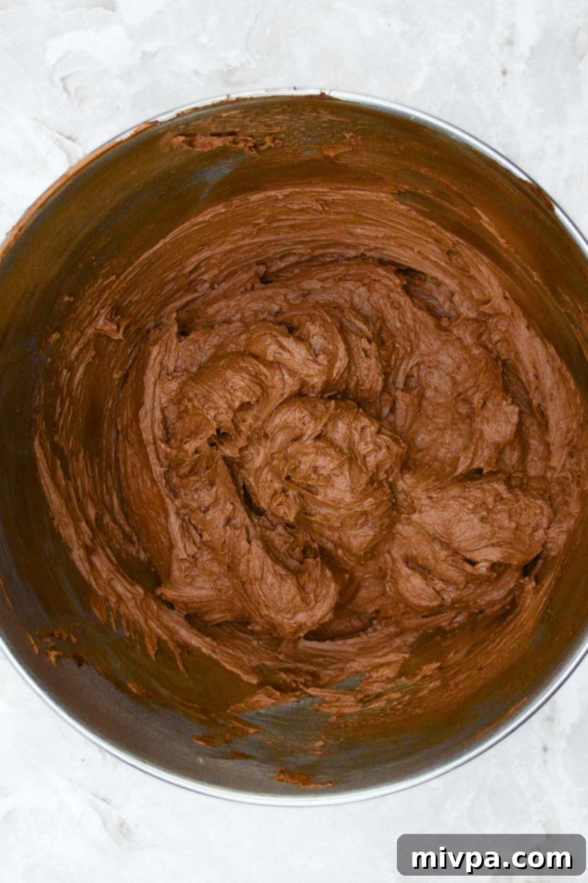 Pumpkin Chocolate Chip Cupcakes (Gluten-Free, Dairy-Free) Smooth and creamy chocolate frosting in a metal mixing bowl, ready for piping.