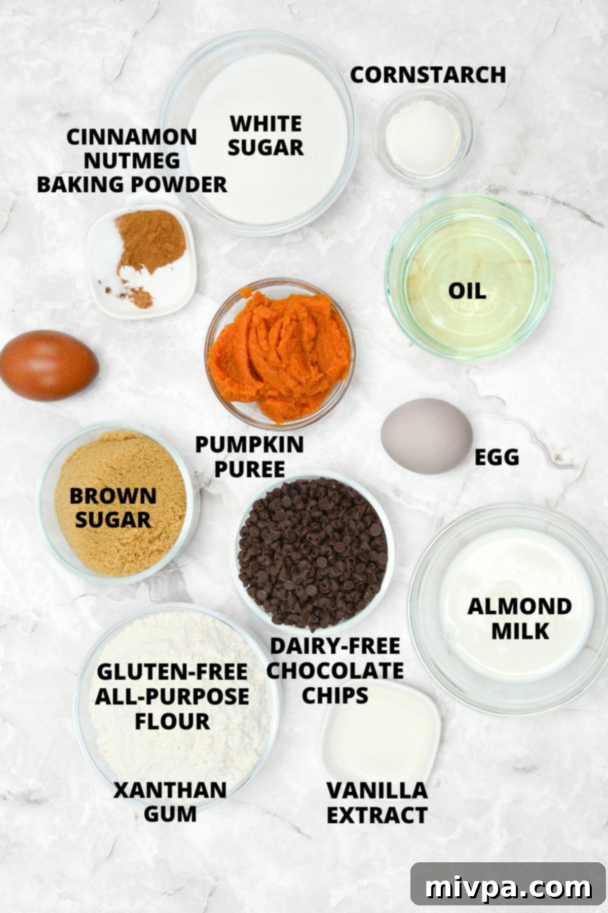 Gluten-Free Pumpkin Cupcakes Recipe (Dairy-Free) Ingredients for gluten-free pumpkin cupcakes recipe laid out on a marble board, including pumpkin puree, flour, spices, and chocolate chips.