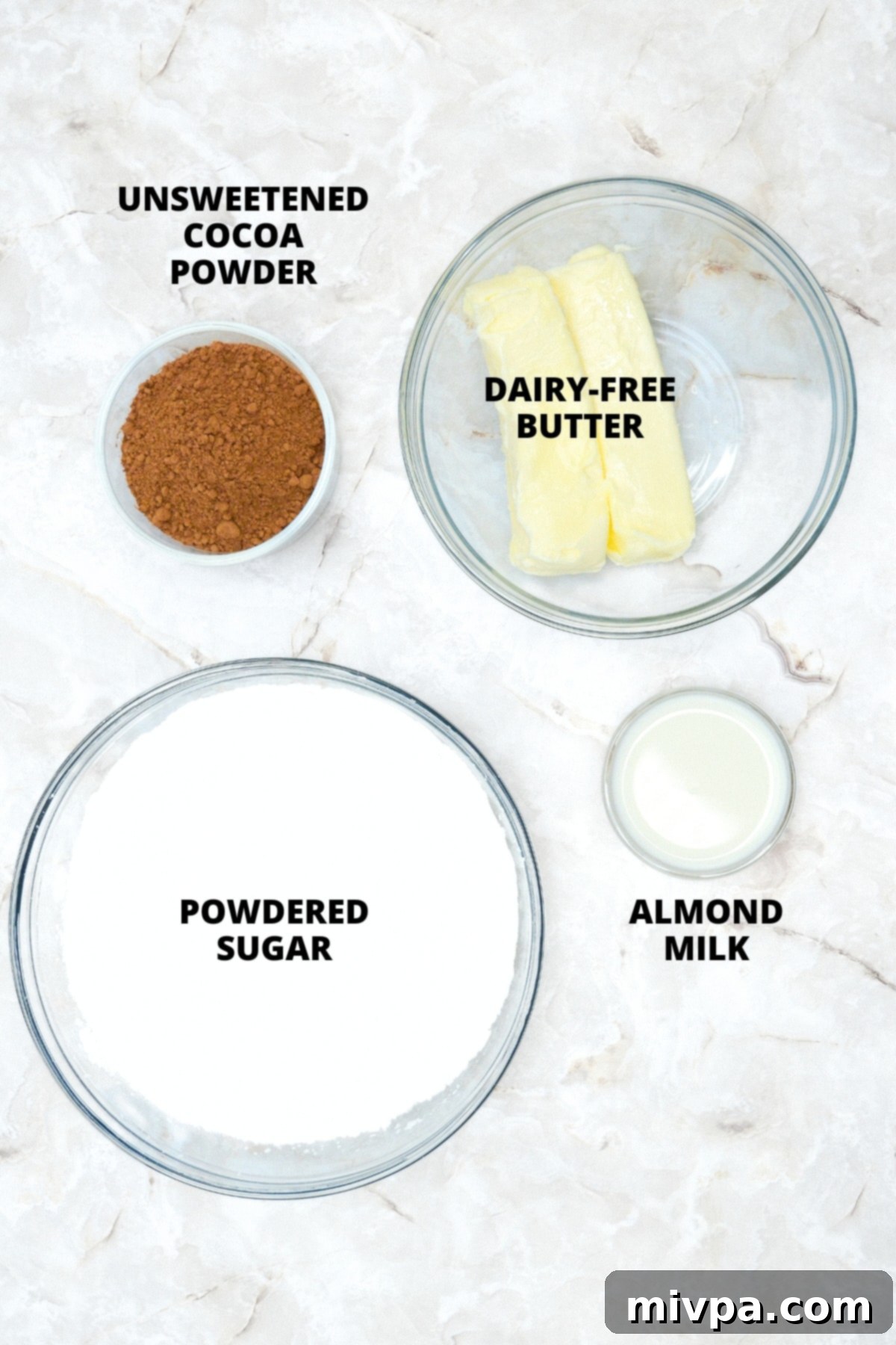 Gluten-Free Pumpkin Cupcakes Recipe (Dairy-Free) Ingredients for dairy-free chocolate frosting laid out on a marble board, featuring cocoa powder, powdered sugar, and dairy-free butter.