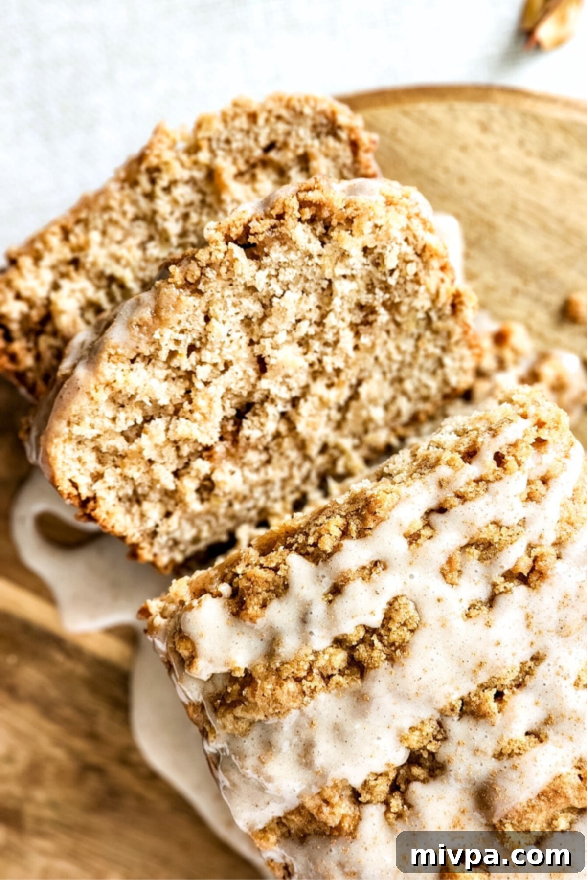 Gluten-Free Apple Cinnamon Bread (Vegan) Up close shot of a delicious apple cinnamon loaf with golden brown crumble and glaze.