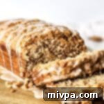 Effortless Plant-Based Gluten-Free Apple Loaf 2 Half-sliced loaf of apple bread on a wooden board with a glaze.