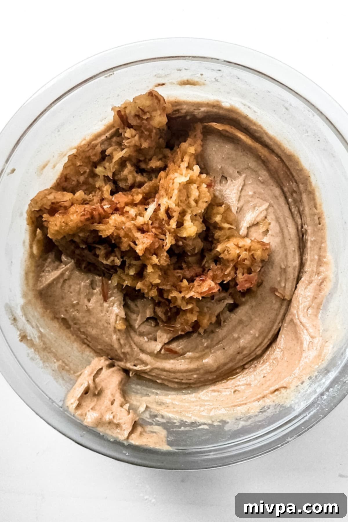 Gluten-Free Apple Cinnamon Bread Recipe (Vegan) Grated apples being folded into the apple bread batter in a glass bowl.
