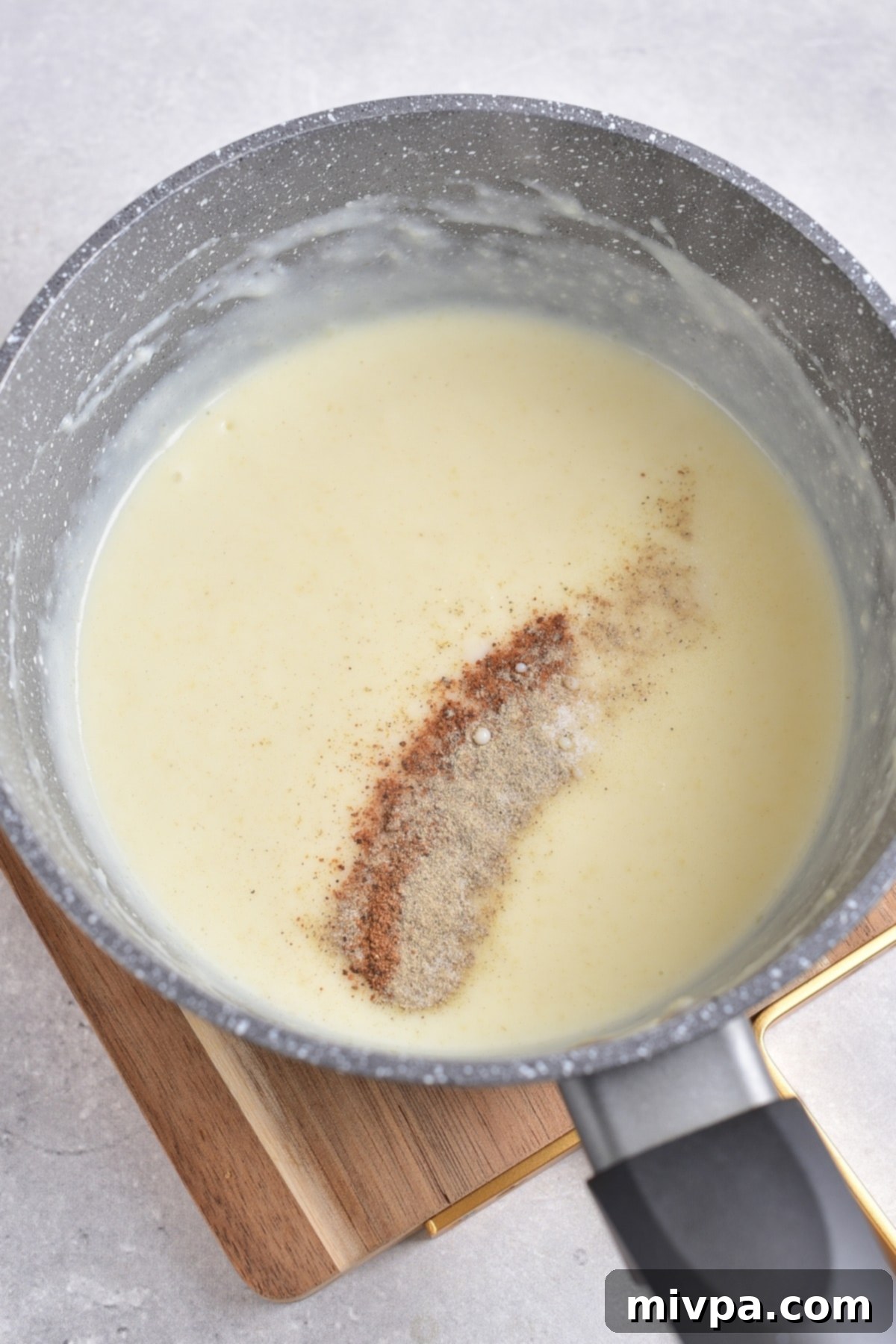 A pot of cream sauce sprinkled with spices.