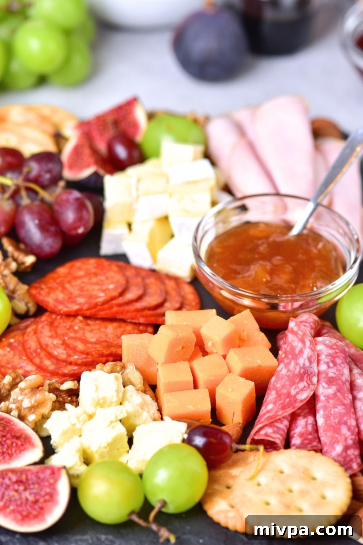 Up close view of cheeses and meats on slate.