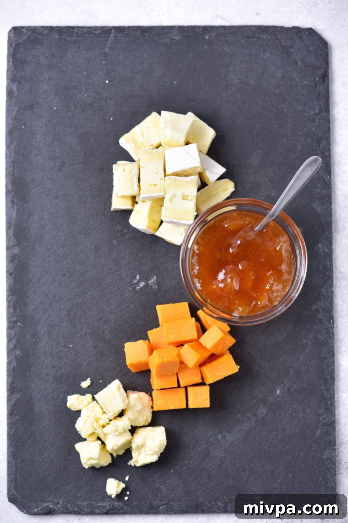 Cheeses and chutney on slate.