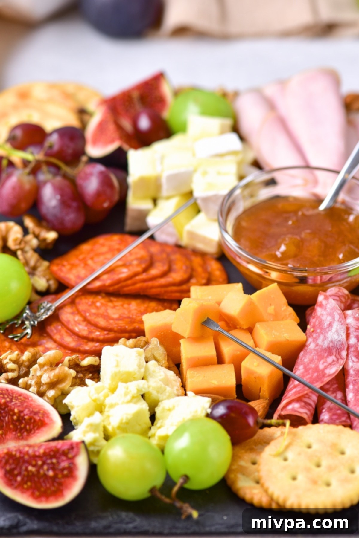 Figs, grapes, crackers and deli meats on board.