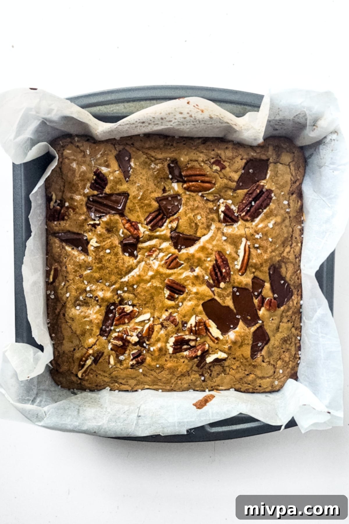 Freshly baked chocolate pecan blondies, still warm from the oven, with a glistening top.