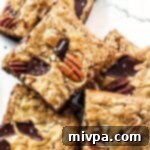 Close-up of a fudgy chocolate pecan bar with visible nuts and chocolate pieces.