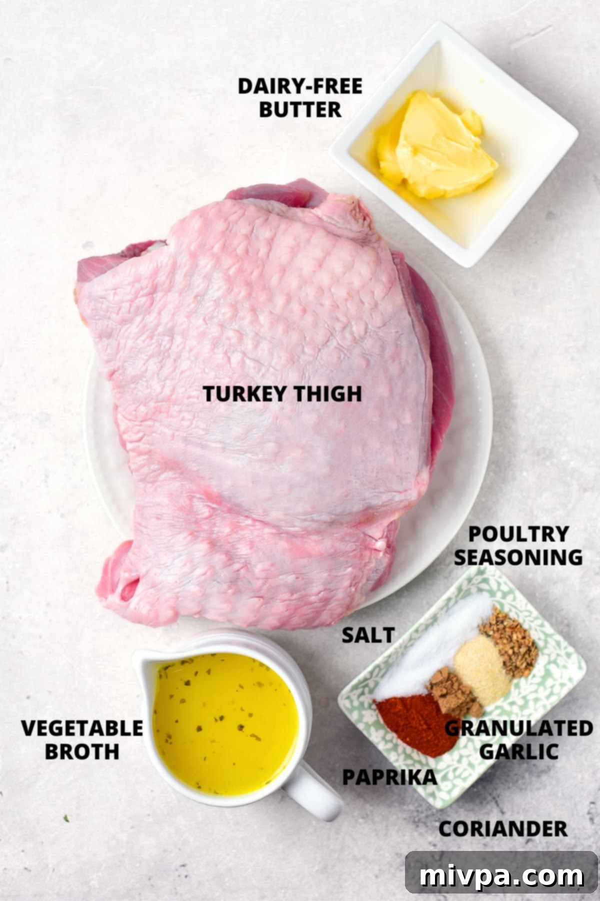 Oven Roasted Turkey Thighs Recipe (Gluten-Free, Dairy-Free) Ingredients for roasted turkey thighs laid out on a wooden board: turkey thighs, broth, dairy-free butter, and various spices.