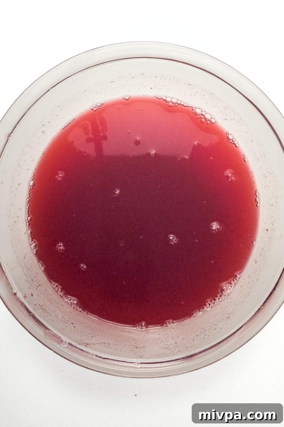 Freshly prepared cranberry juice in a clear glass bowl, showcasing its vibrant color and smooth texture, ready for final serving.