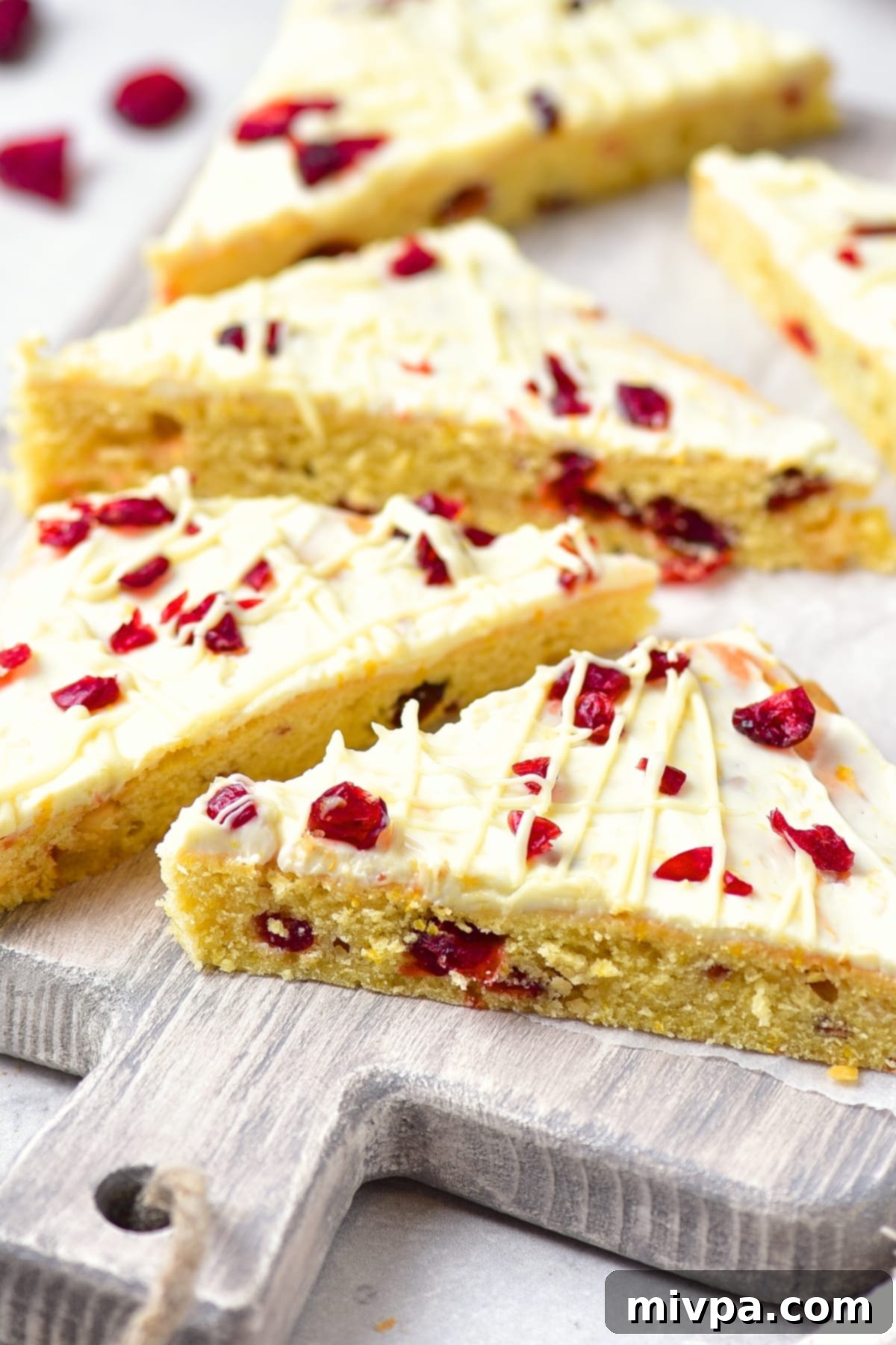 Gluten-Free Cranberry Bliss Bars (Dairy-Free Starbucks Copycat) Delicious gluten-free cranberry bliss bars topped with white frosting, orange zest, and dried cranberries on a wooden board, ready for the holidays.
