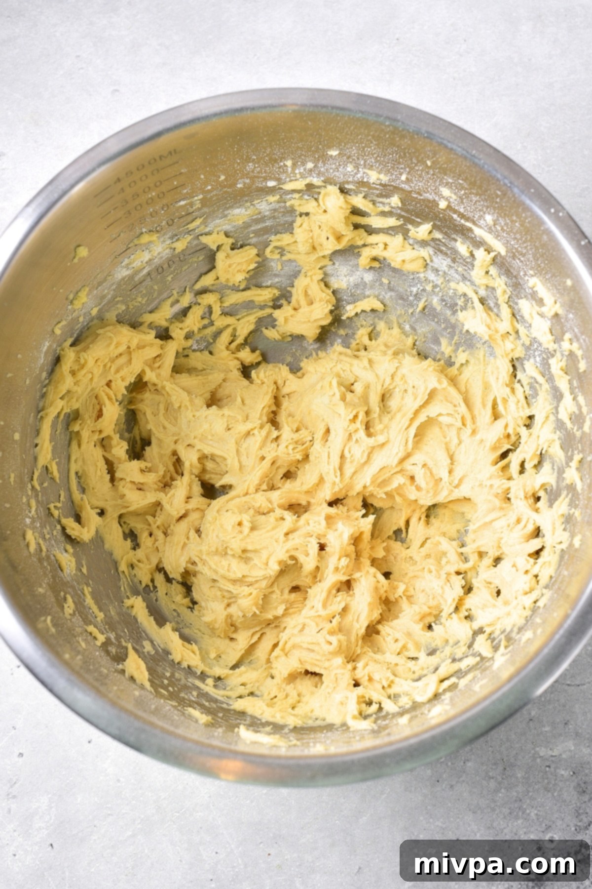 Dairy-Free Cranberry Bliss Bars (Gluten-Free Batter) Thick, yellow blondie batter in a metal mixing bowl, showcasing its consistency after all ingredients have been mixed.