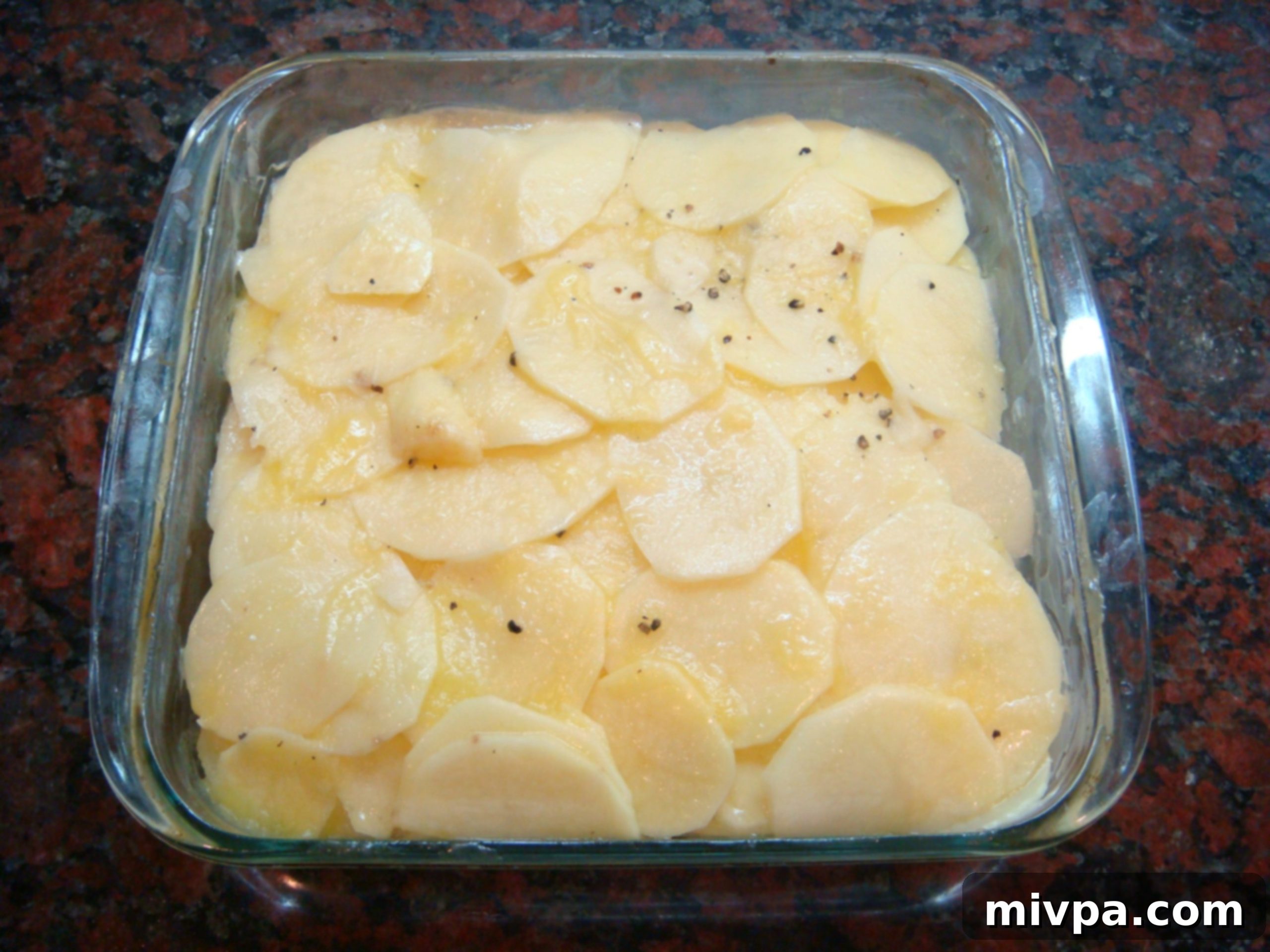Close-up of thin potato slices carefully arranged and layered in a baking pan