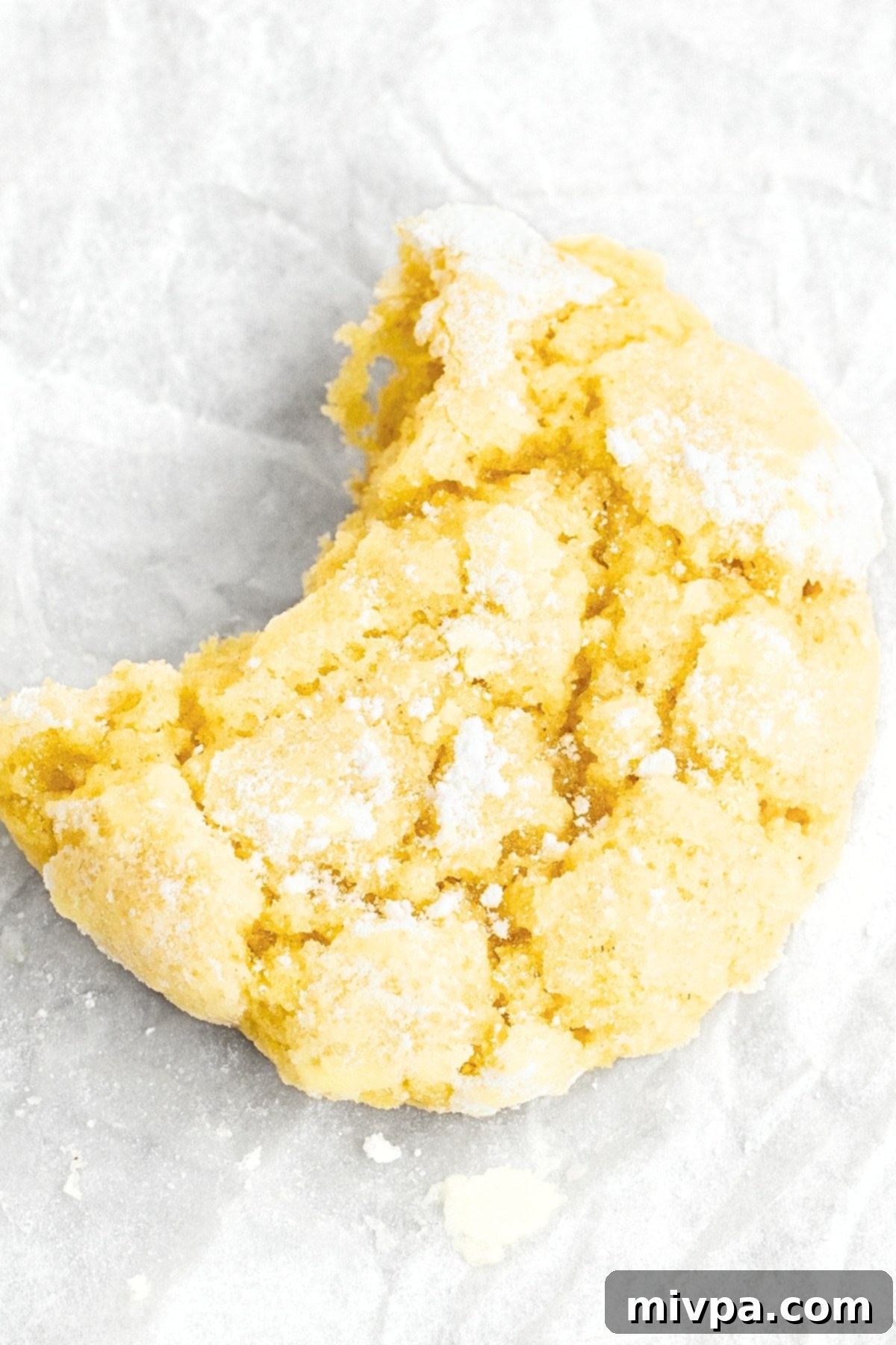 Up close shot of a half-eaten lemon crinkle cookie.