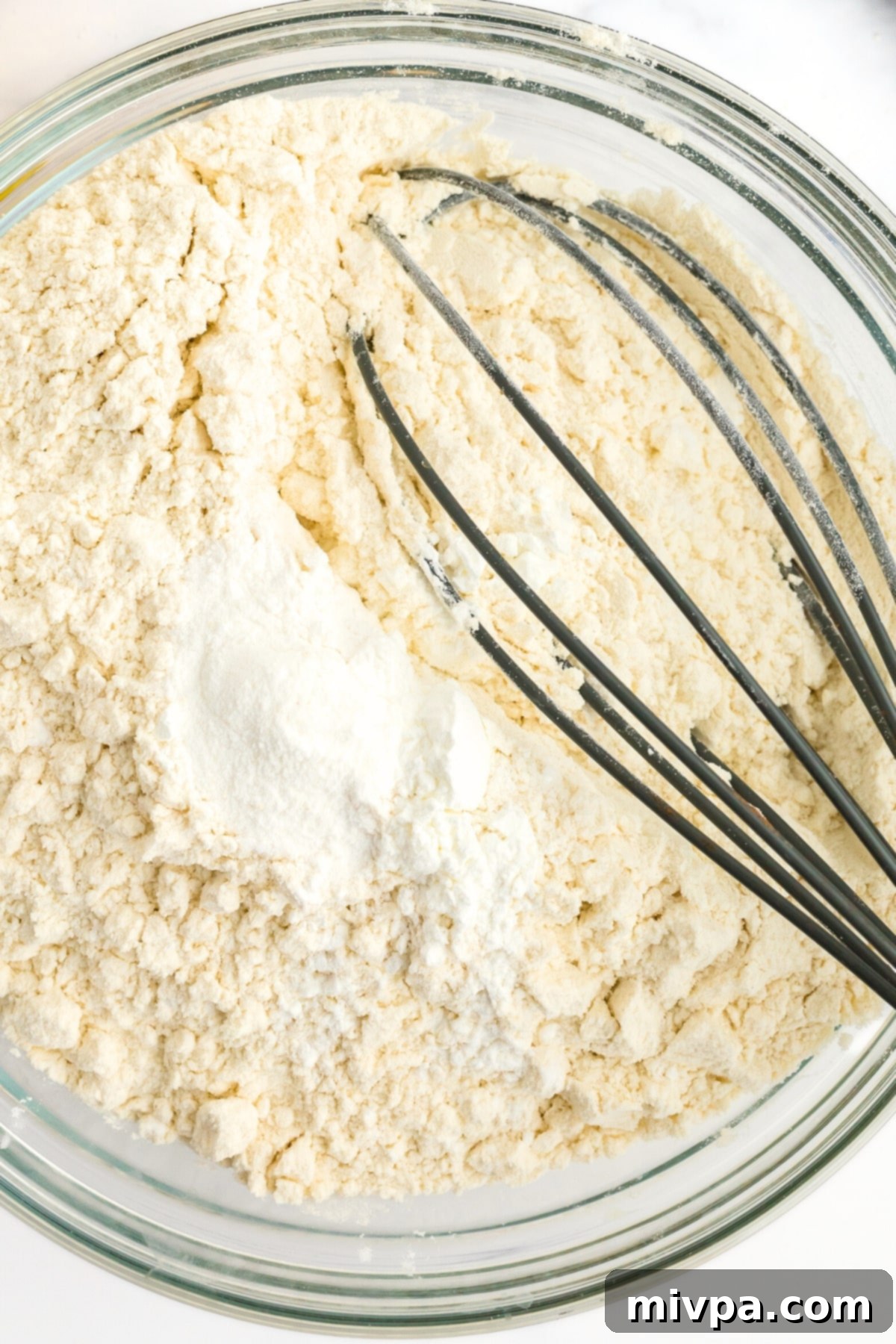 Whisking flour mixture in glass mixing bowl.