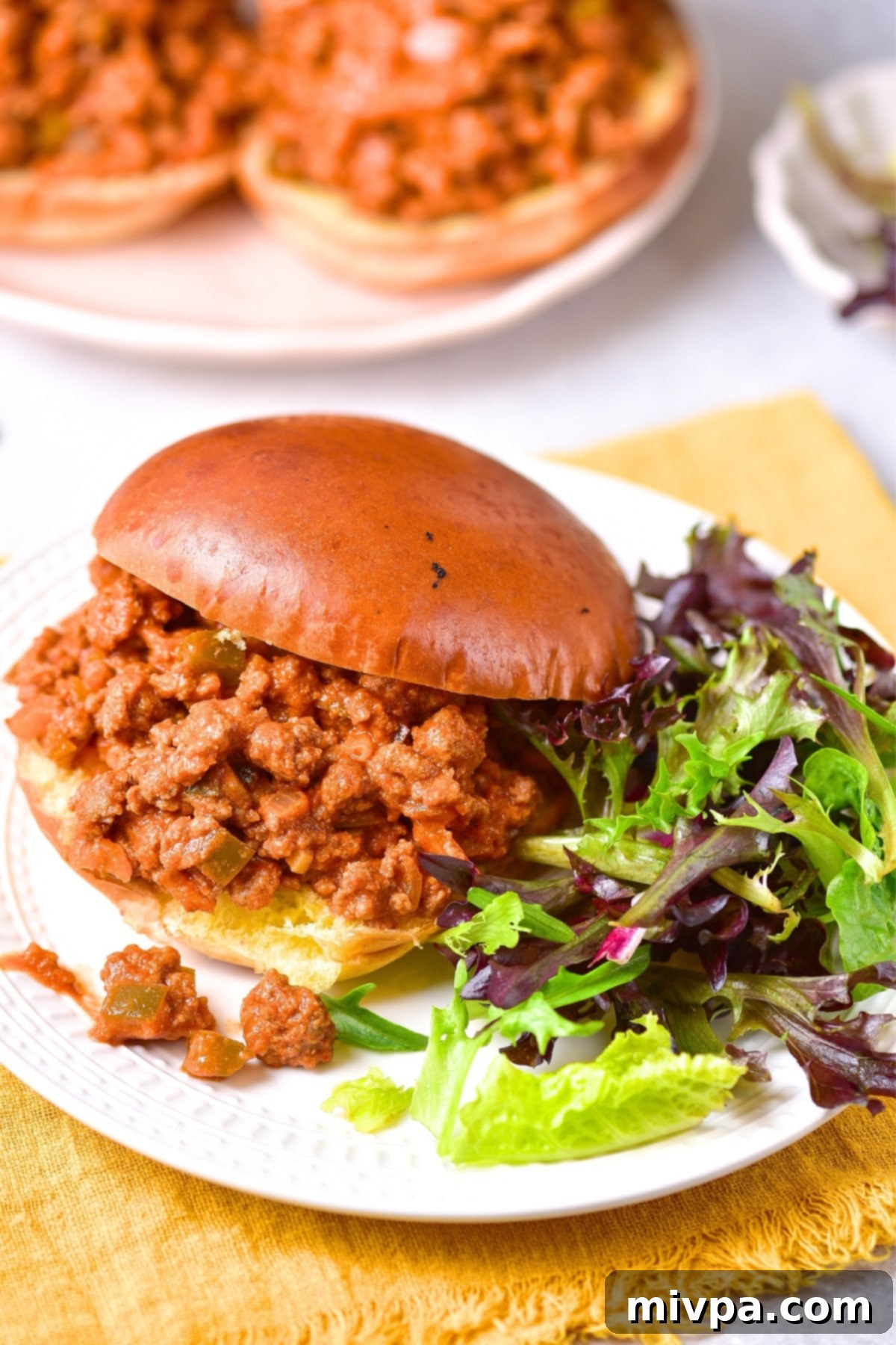 Homemade Sloppy Joes (Gluten-Free, Dairy-Free) Sloppy joe burger and salad on white plate.