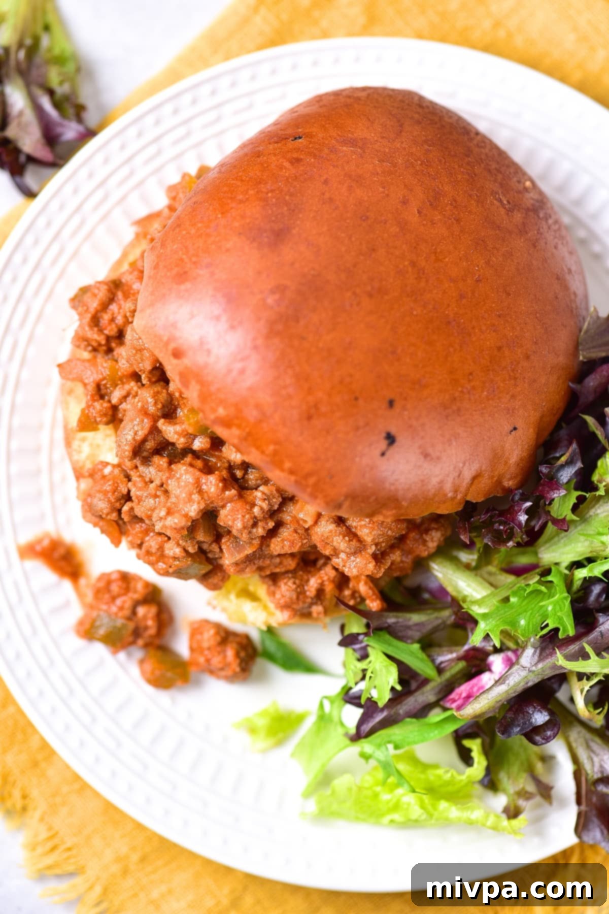 Gluten-Free Sloppy Joes Recipe (Dairy-Free) Top down view of sloppy joe and salad on white plate.