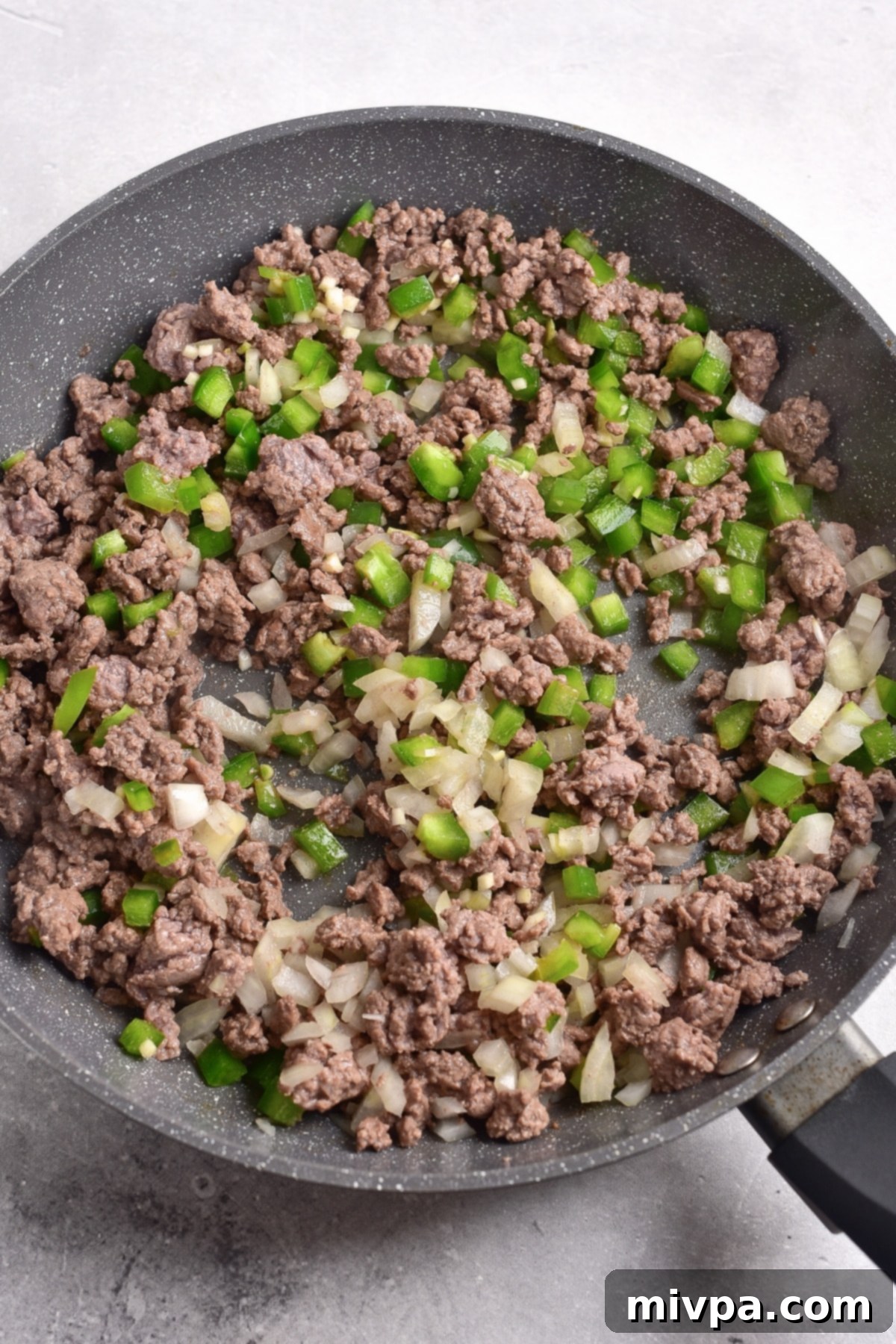 Gluten-Free Dairy-Free Sloppy Joes Cooking diced bell peppers and onions with ground beef in skillet.