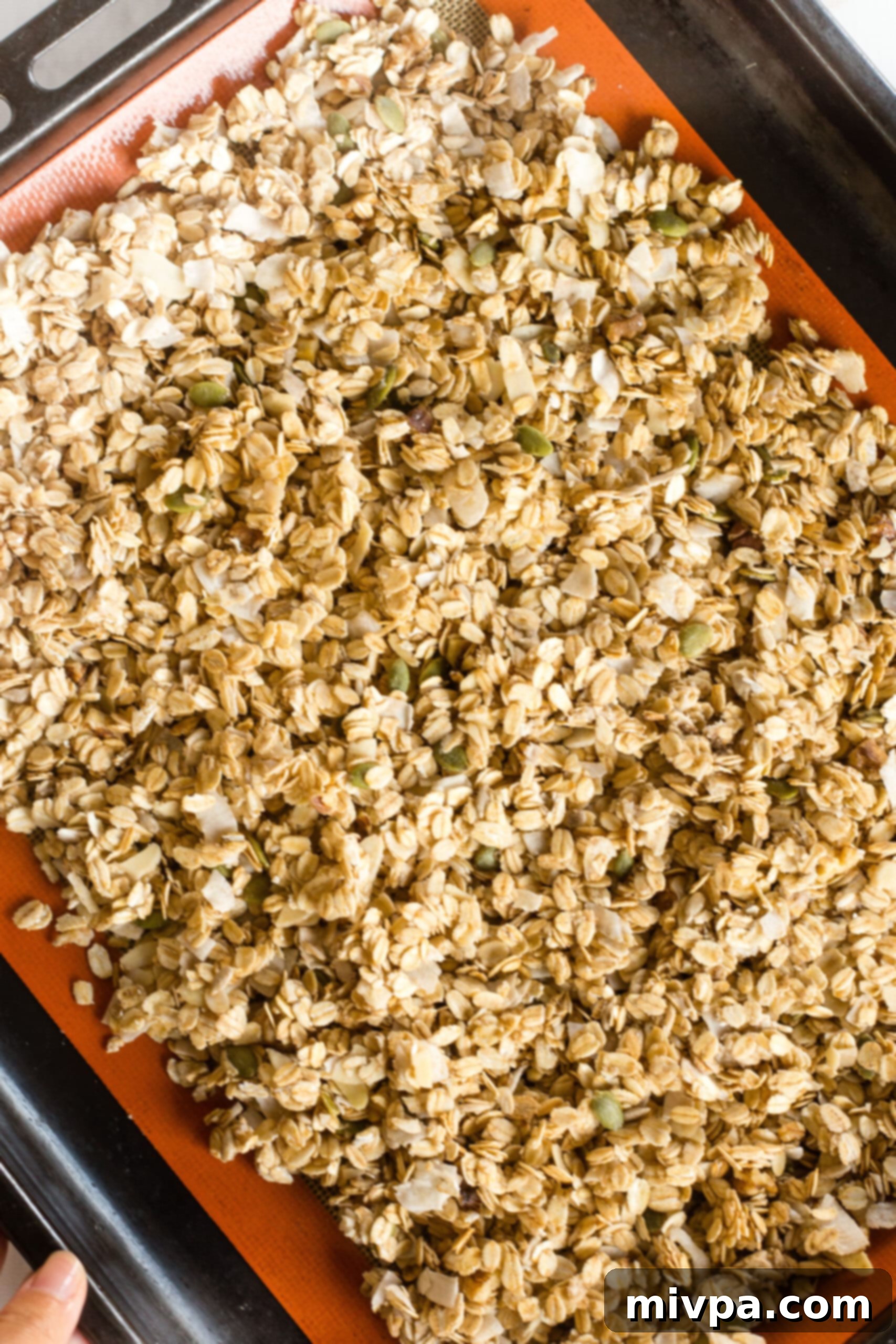 Vegan Granola (Gluten-Free) Granola mixture spread out on silpat-lined baking sheet.