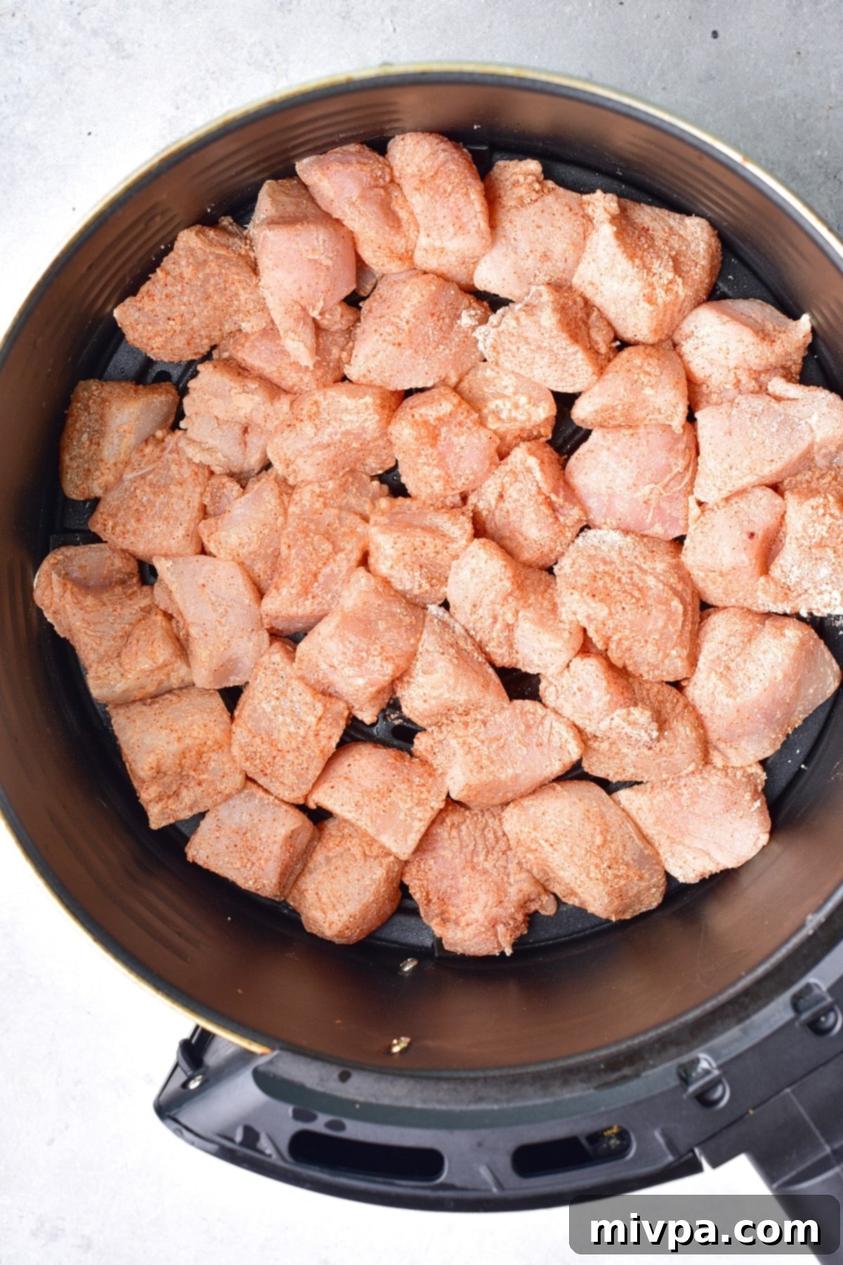Raw chicken pieces in air fryer basket