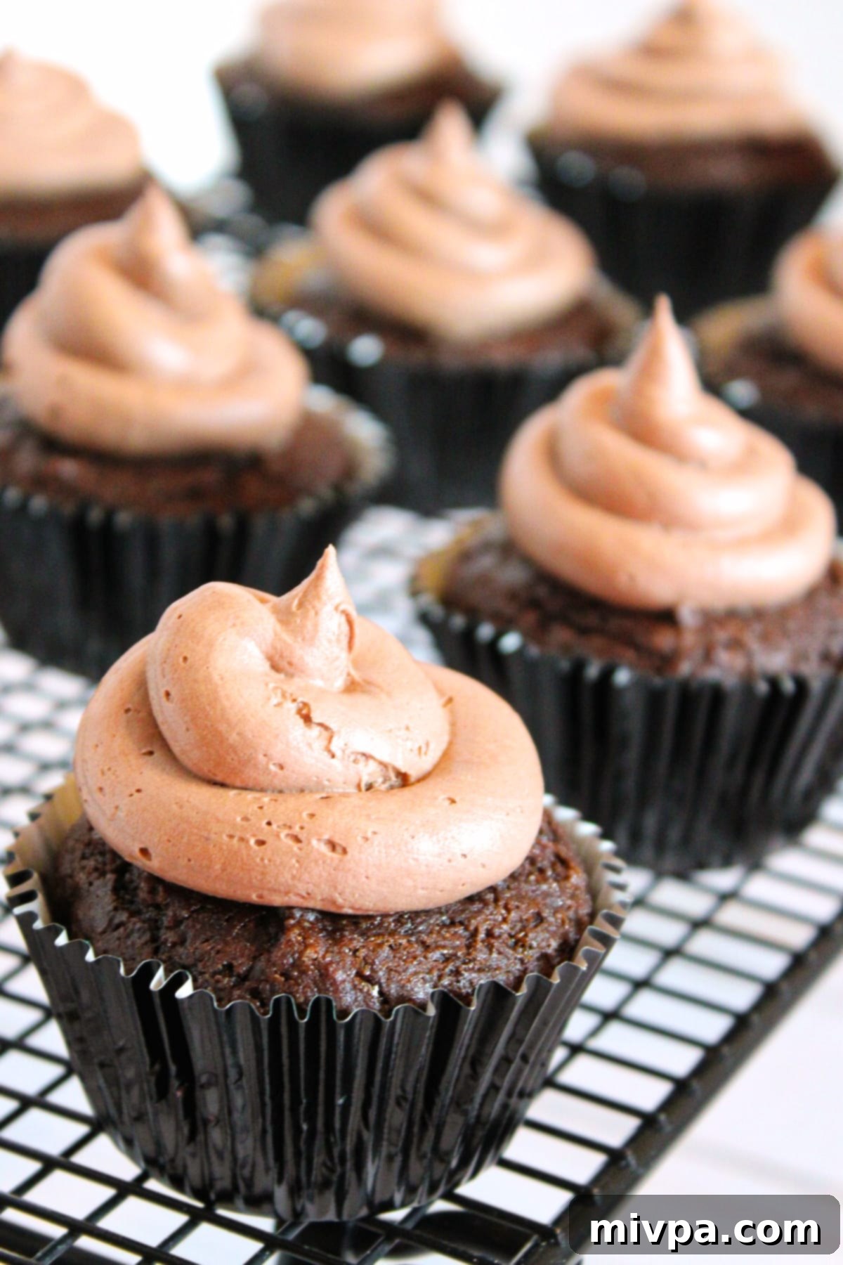 Gluten-free dairy-free chocolate cupcakes arranged neatly on a wire cooling rack, ready for frosting.