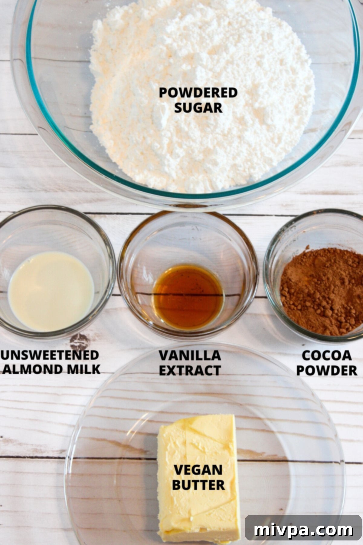 Ingredients for gluten-free chocolate buttercream frosting laid out on a cutting board, including dairy-free butter, powdered sugar, cocoa, and vanilla.