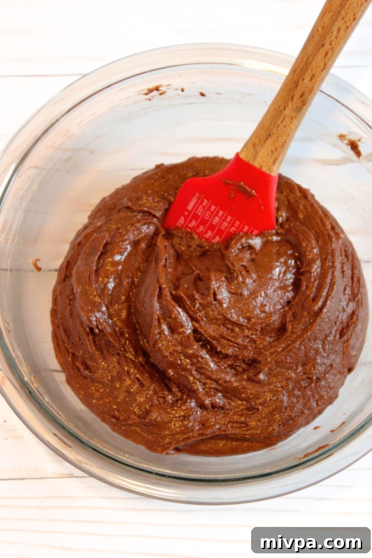 Close-up shot of chocolate cupcake batter being mixed in a bowl, showing its smooth consistency.