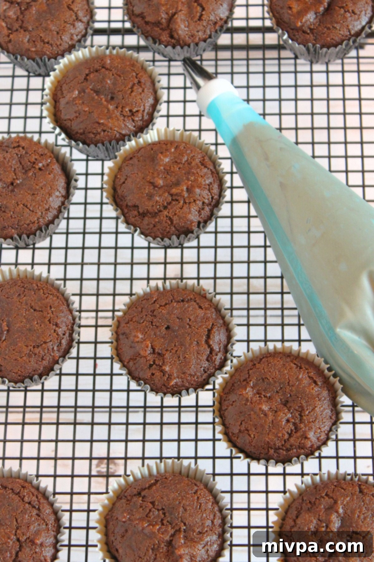 Beautifully frosted gluten-free chocolate cupcakes on a wire rack, topped with swirls of chocolate buttercream.
