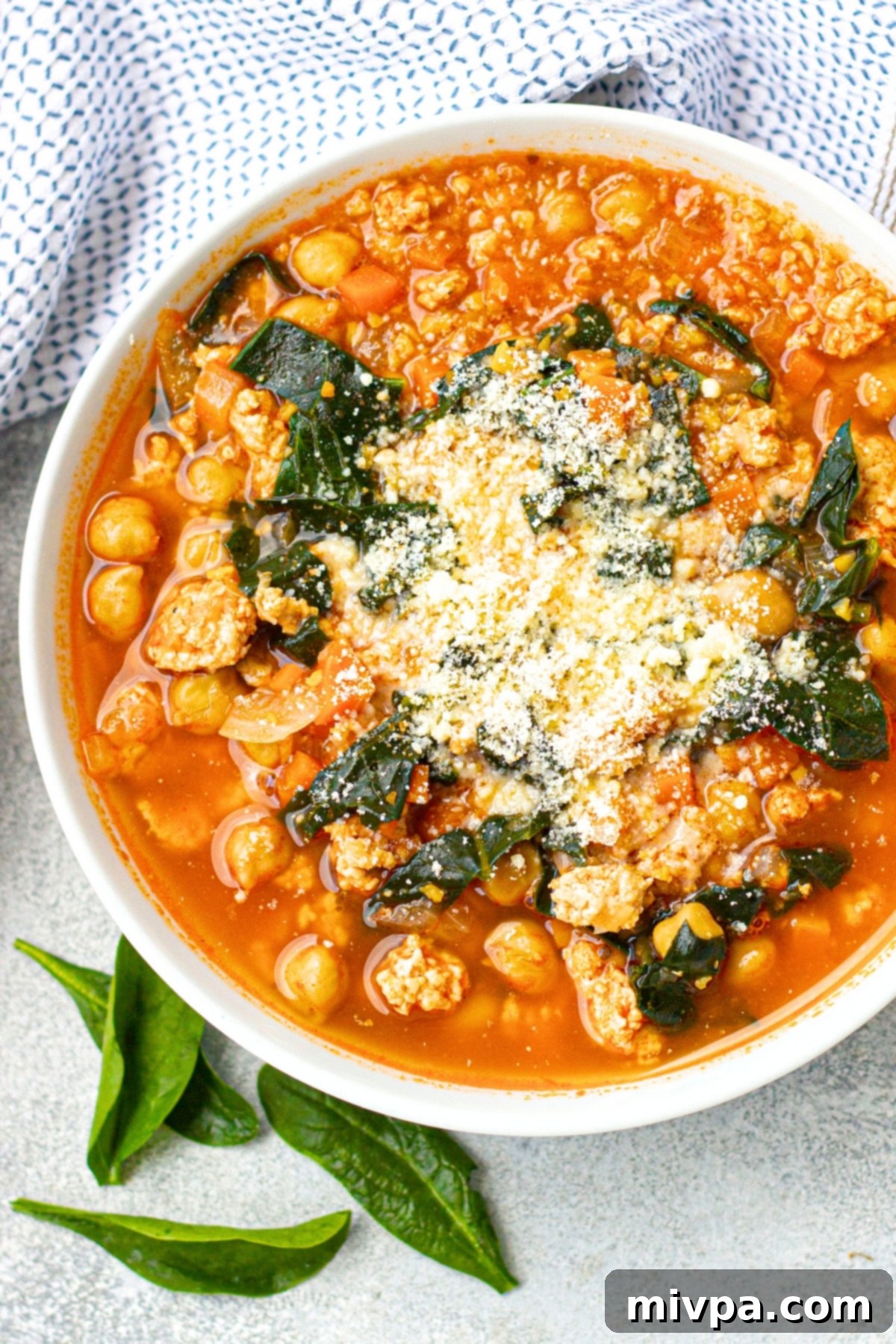 Hearty Chickpea Kale Soup (Gluten-Free, Dairy-Free) Top down view of a bowl of chickpea kale soup sprinkled with parmesan cheese.