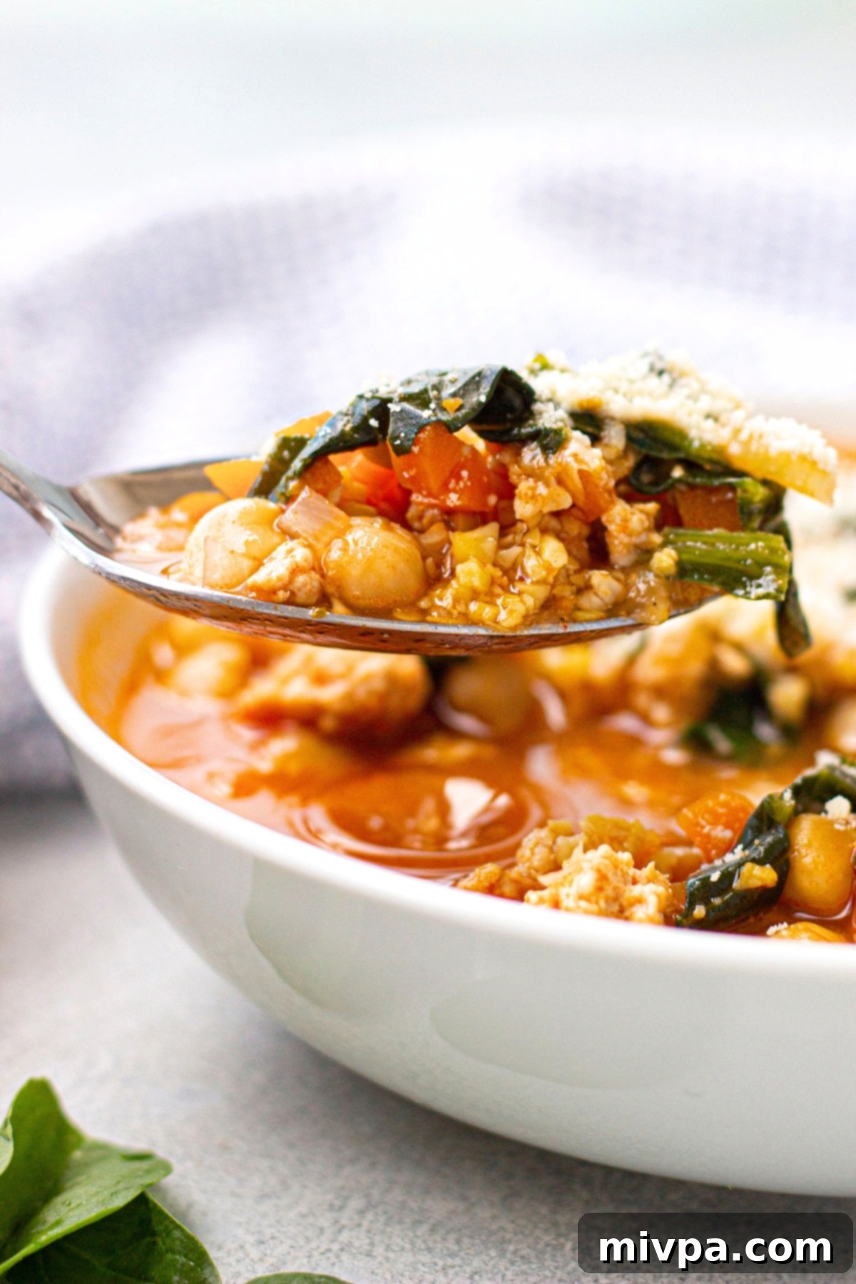 Hearty Chickpea Kale Soup (Gluten-Free, Dairy-Free) Holding up a spoonful of chickpea kale soup.