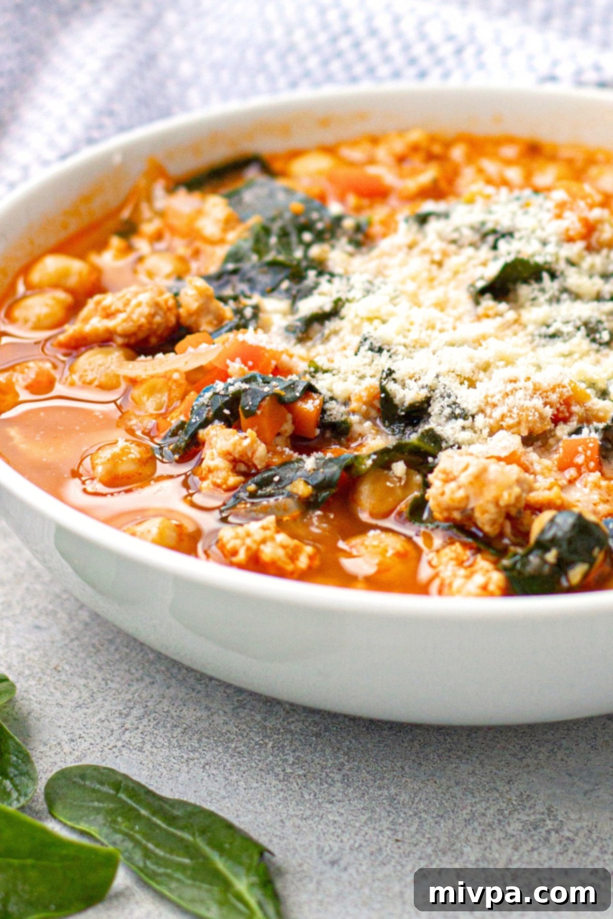 Kale Chickpea Soup (Gluten-Free, Dairy-Free) Up close view of a bowl of kale chickpea soup sprinkled with parmesan.