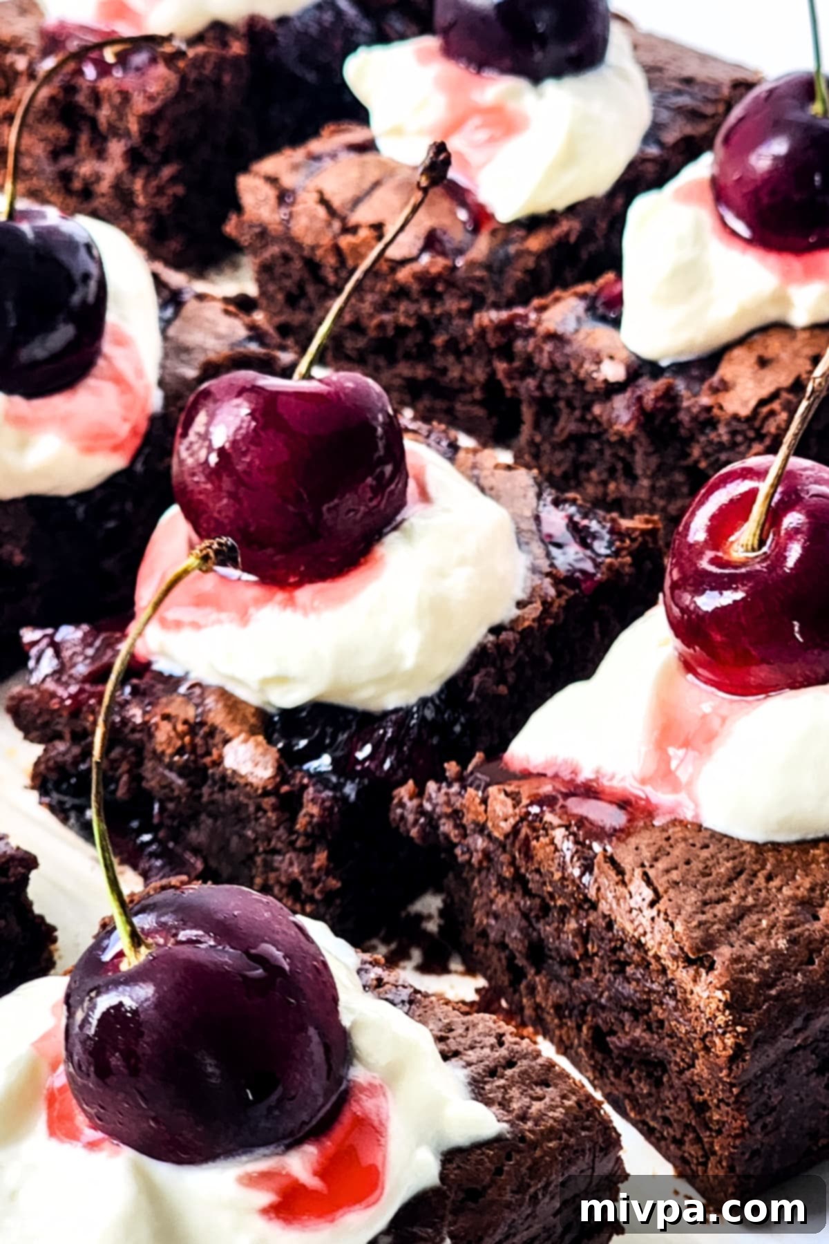 Easy Black Forest Brownies (Gluten-Free, Dairy-Free) Close-up view of a fudgy Black Forest brownie, generously topped with dairy-free whipped cream and a fresh cherry, resting on a rustic wooden board.