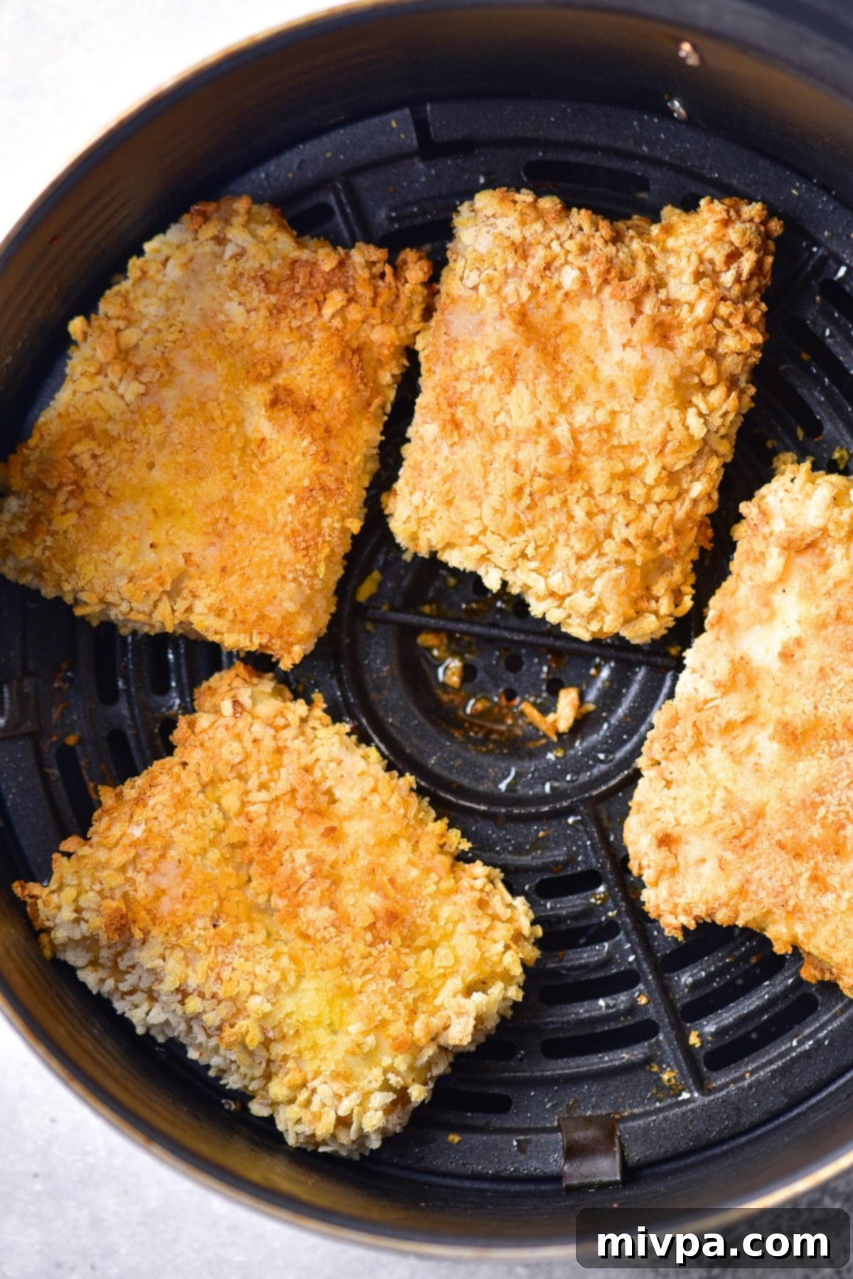 Gluten-free fish cooking in an air fryer with a golden crispy coating.