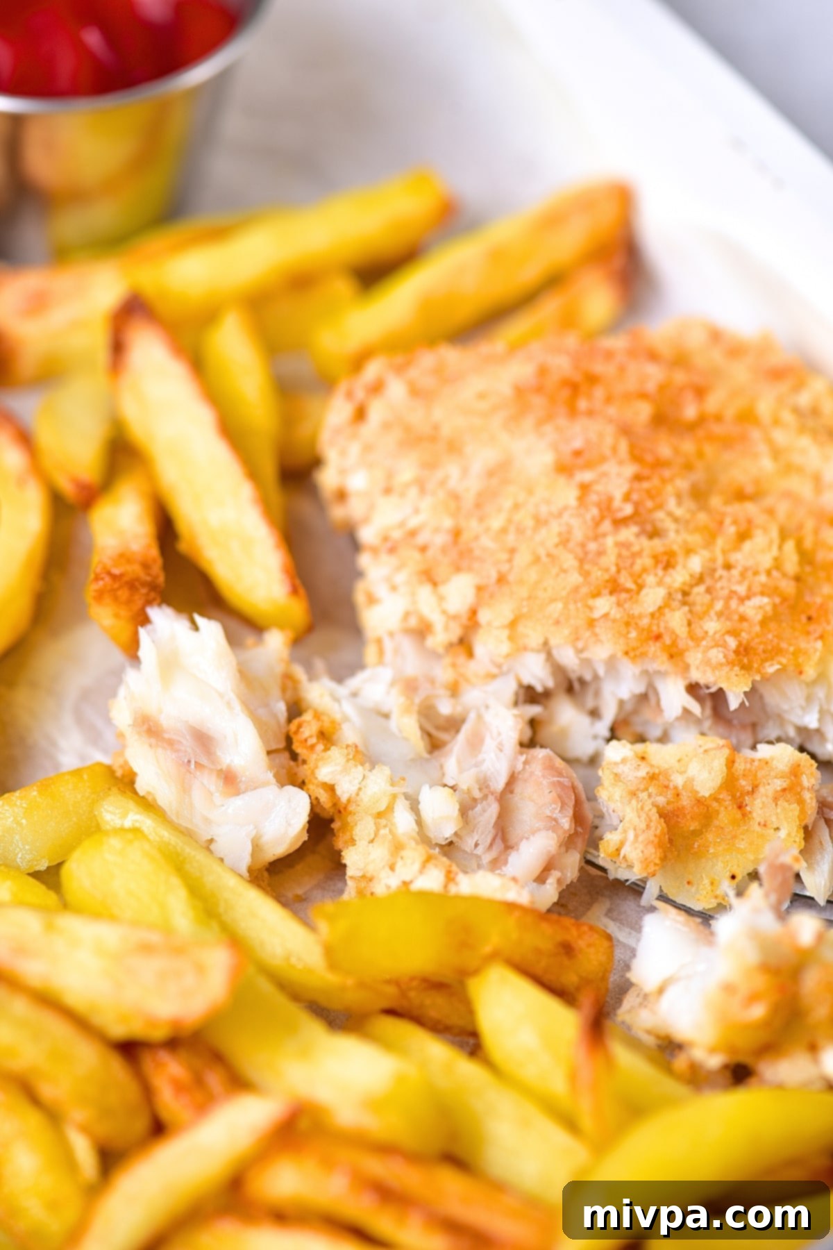 Half-eaten plate of crispy gluten-free fish and chips, showing the flaky fish and golden fries.