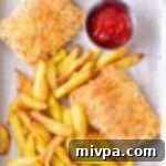 Crispy Gluten-Free Fish and Chips on a parchment-lined tray with lemon.
