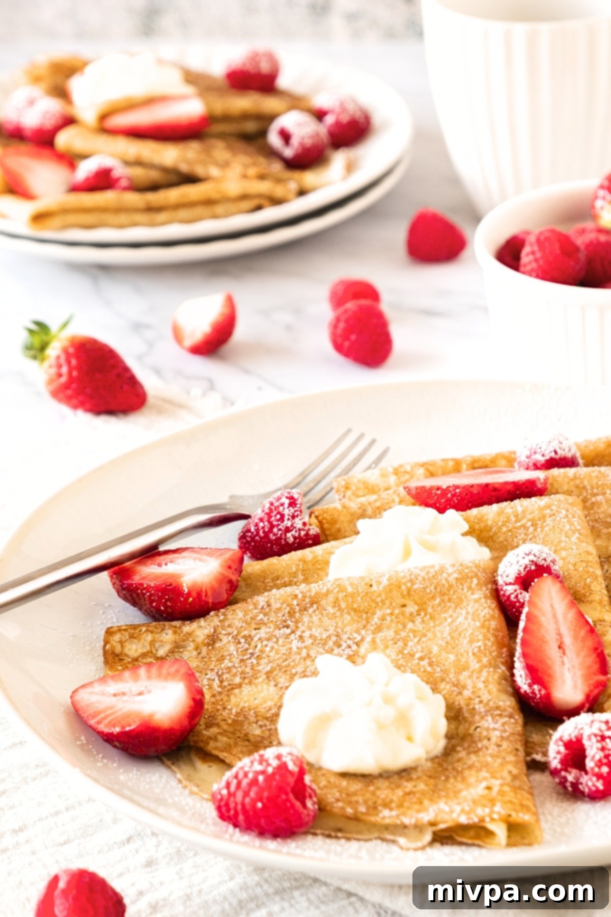 A plate of folded crepes and berries.