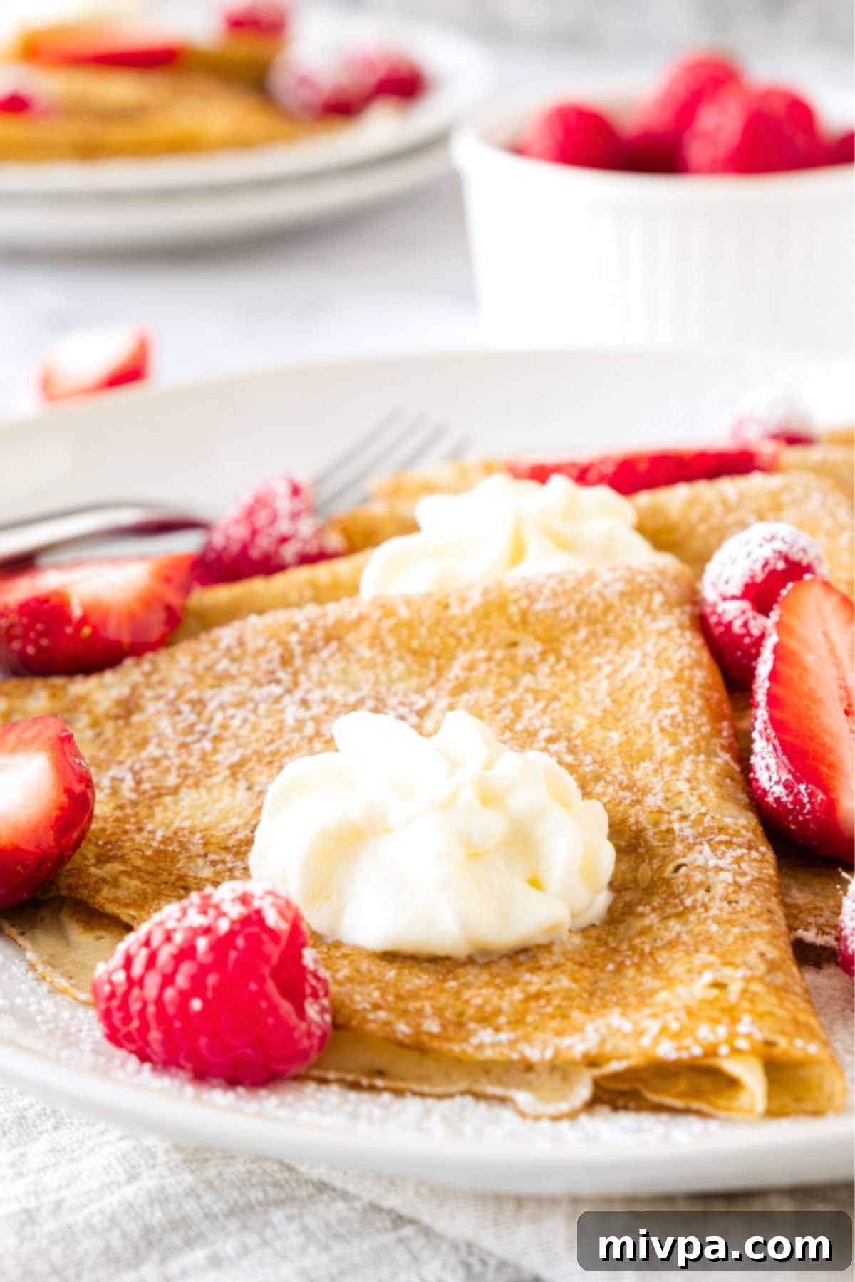 Gluten-Free Dairy-Free Crepes Up close shot of gluten-free dairy-free crepes with berries and whipped cream.
