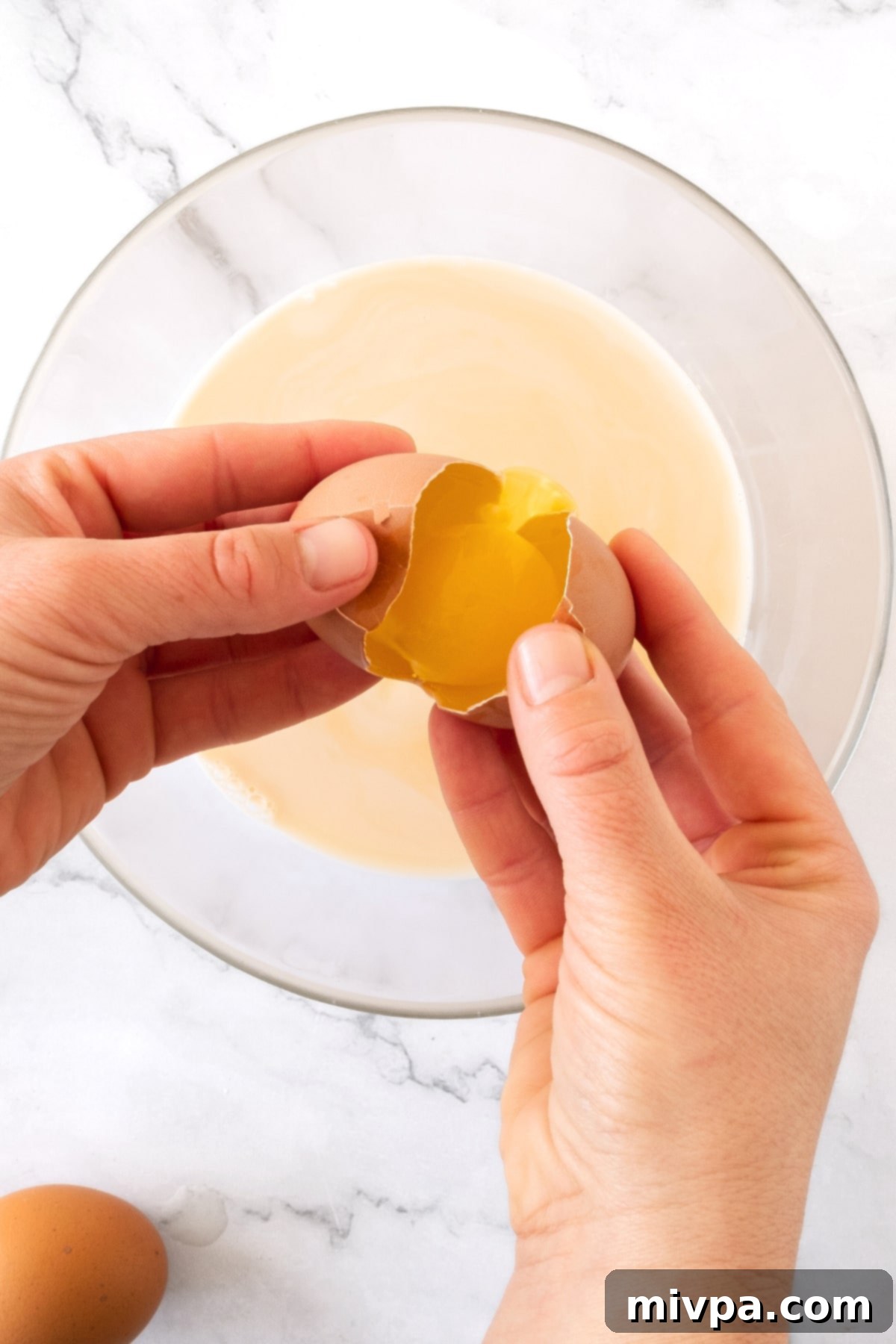 Dairy-Free Gluten-Free Crepes Cracking an egg into a bowl with pale yellow mixture.