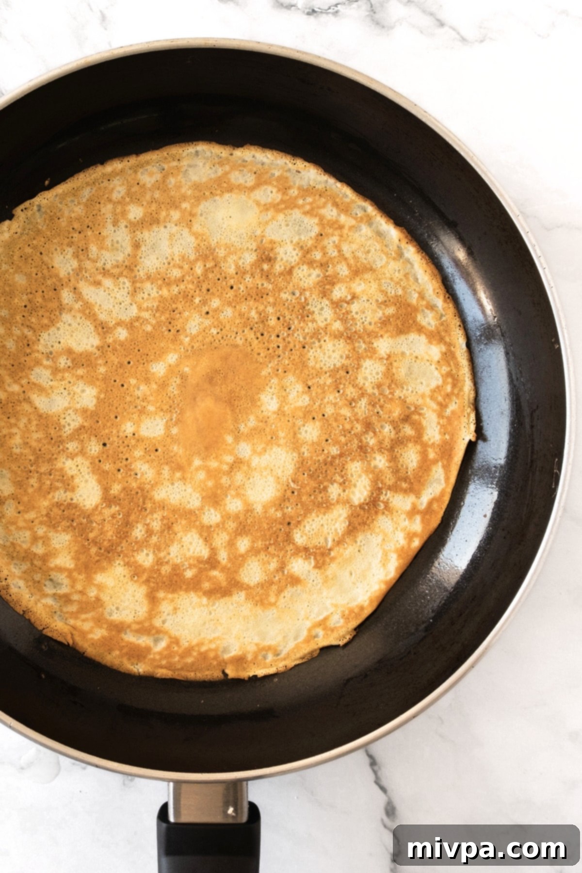A fully cooked crepe in skillet.
