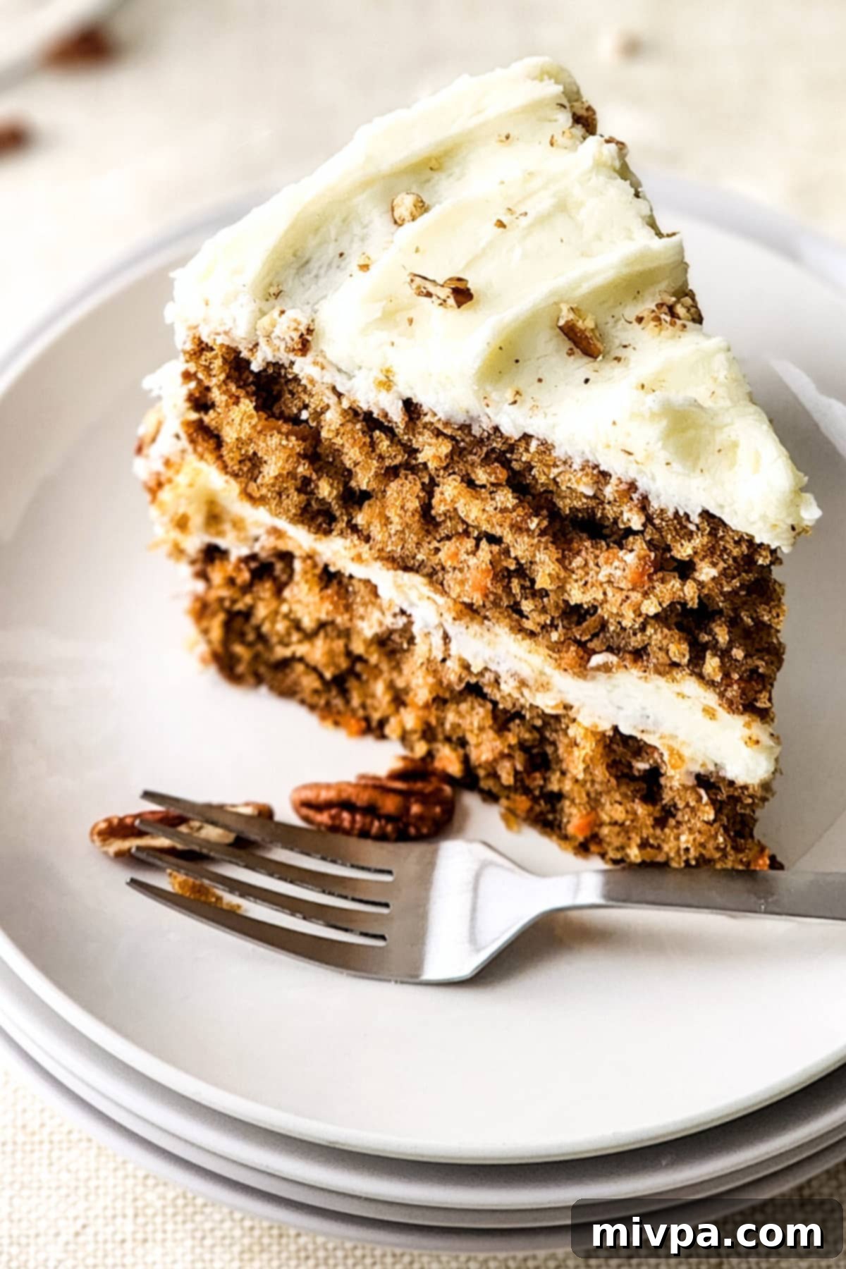Moist Gluten-Free Carrot Cake (Dairy-Free) A slice of moist gluten-free carrot cake and a fork on white plate.