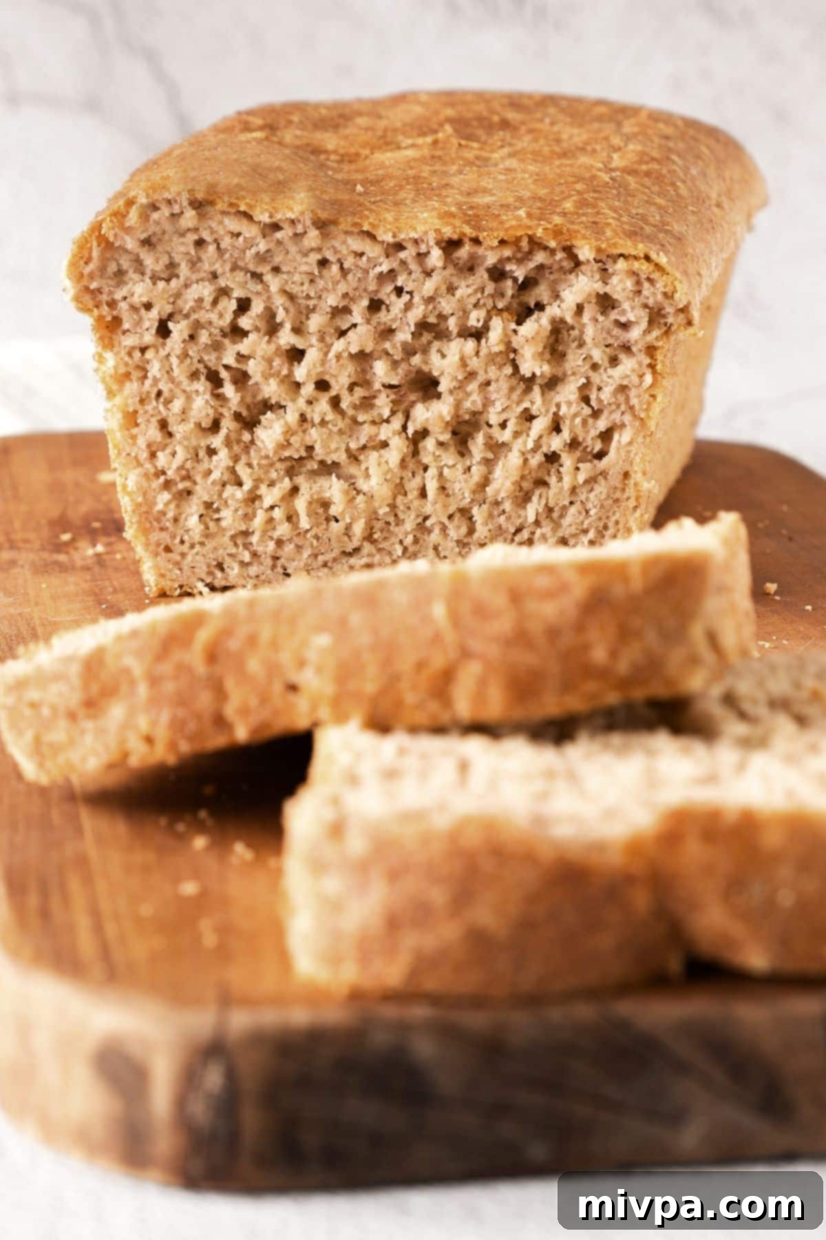Beer Bread (Gluten-Free, Dairy-Free) Close-up shot of a half-sliced loaf of soft, tender gluten-free beer bread on a wooden board, ready to be served.