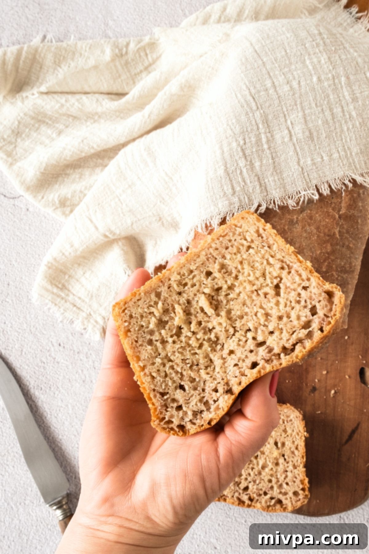 Gluten-Free Dairy-Free Beer Bread Hand holding a fluffy slice of gluten-free dairy-free beer bread against a blurred background.