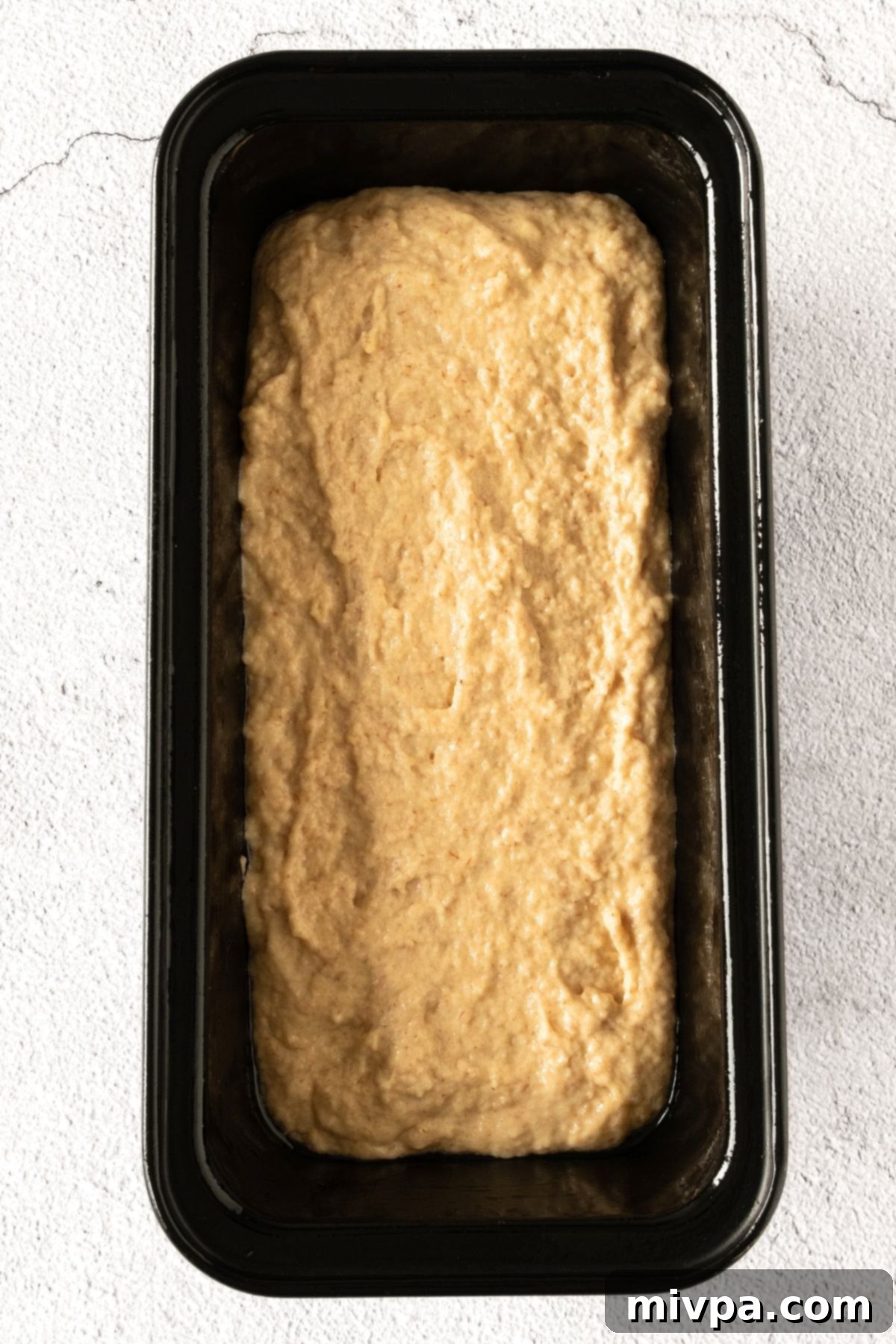 GF Beer Bread (Dairy-Free) Unrisen GF bread dough neatly placed in a metal loaf pan, ready for proofing.