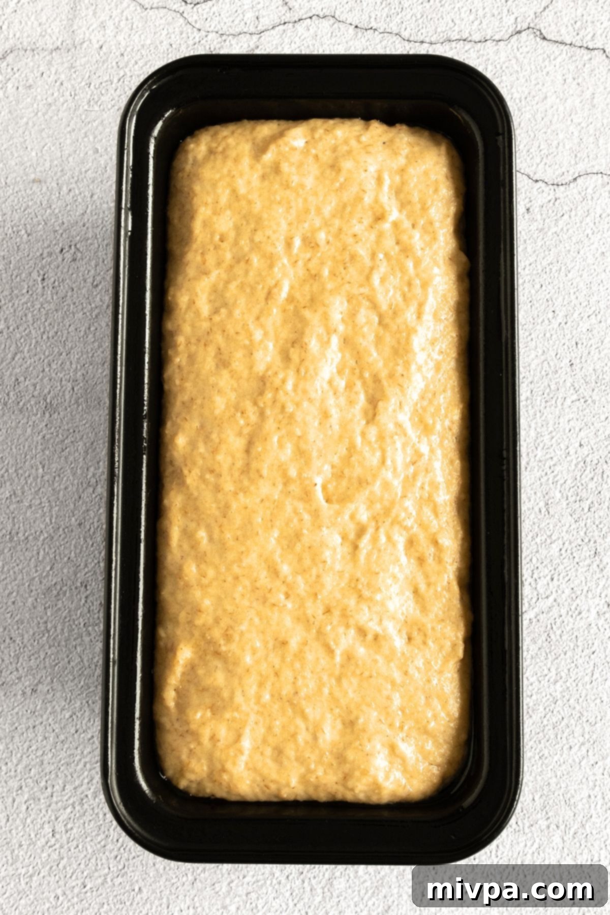Dairy-Free Beer Bread (Gluten-Free) Perfectly risen gluten-free beer bread dough in its pan, covered lightly with a kitchen towel.